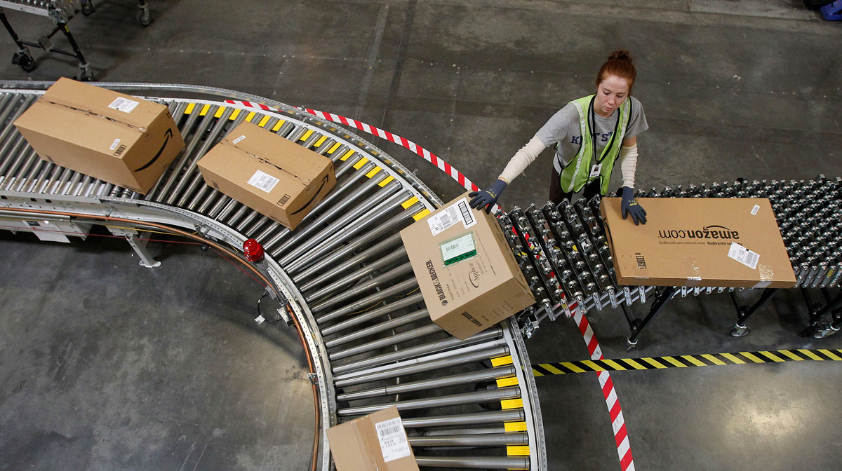 An Amazon worker putting packages on a conveyor belt