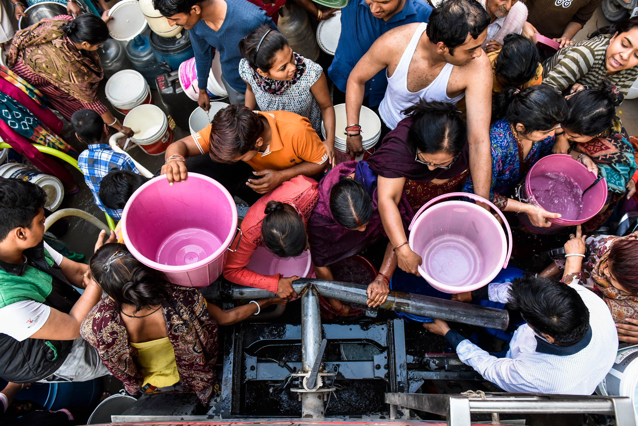 Image of people in India crowding to fill buckets with clean drinking water.