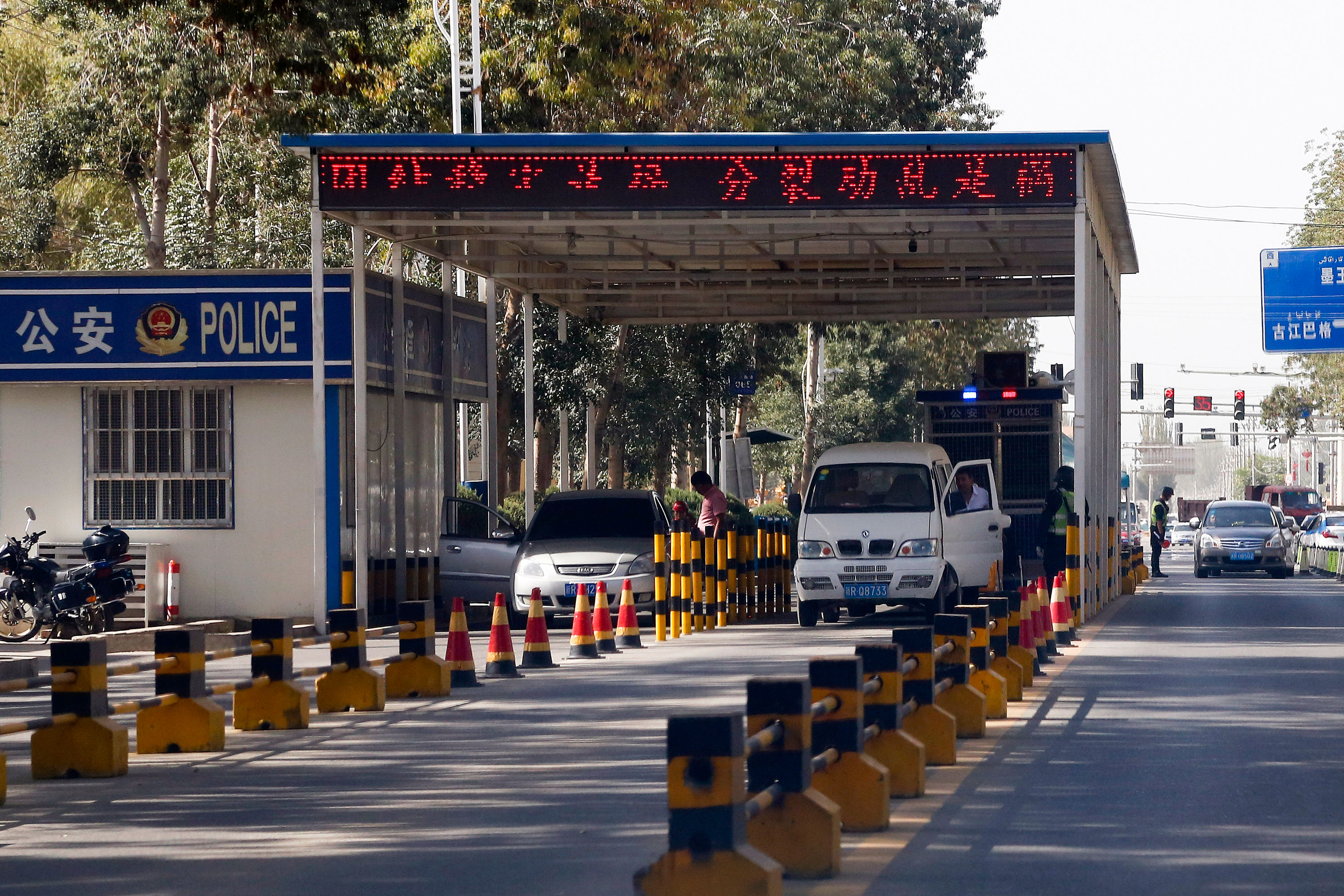 Uighur drivers have their vehicles checked at a police check point in Hotan