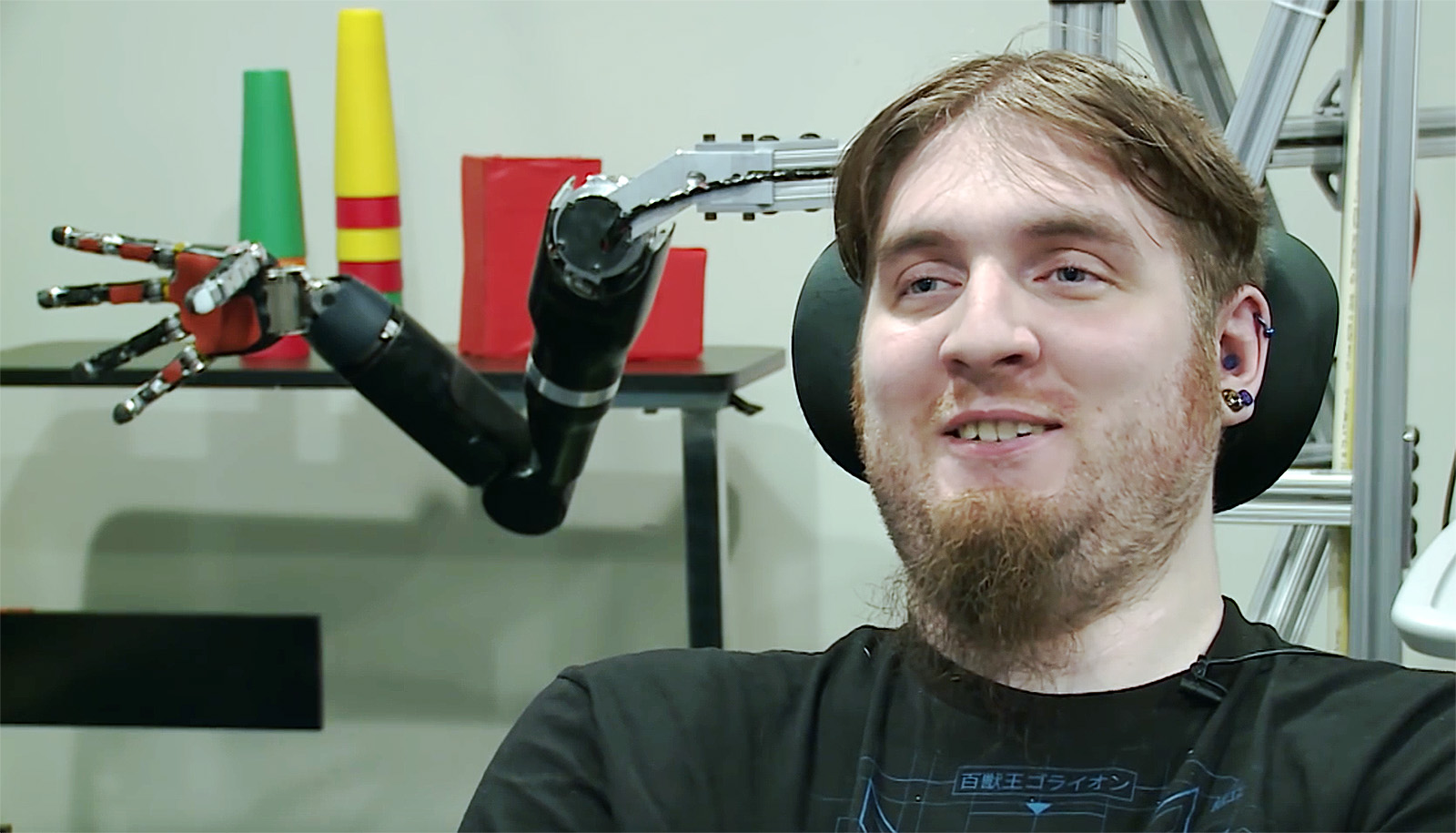 Portrait of Nathan Copeland, one of the first people to have a brain computer interface, with a robot arm behind his head