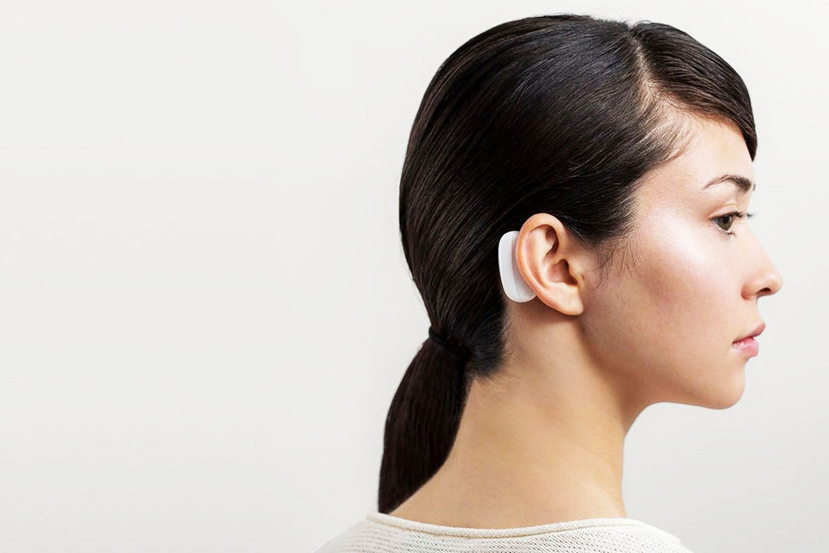 An image of a woman with a device behind her ear