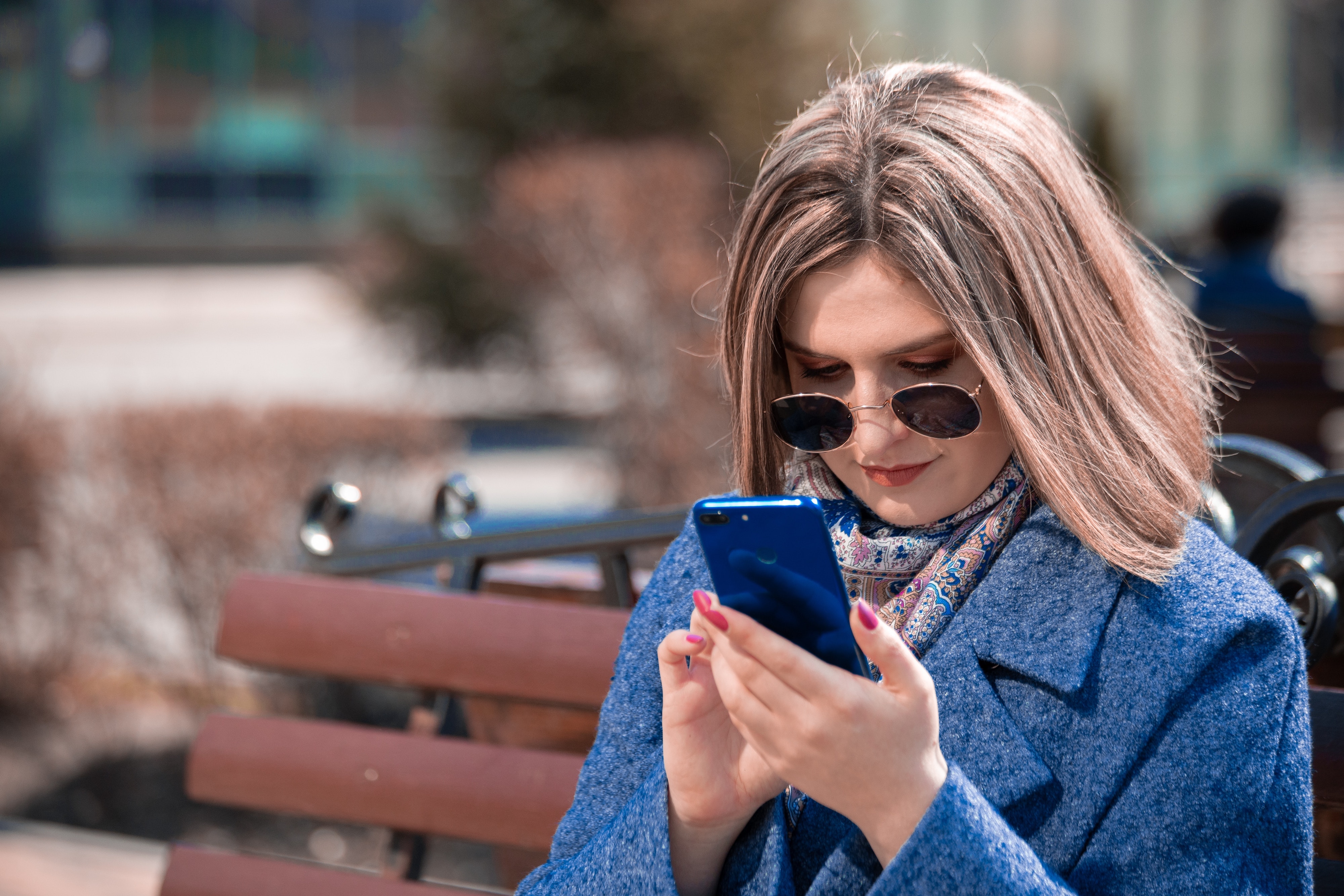 woman looking at phone on park bench