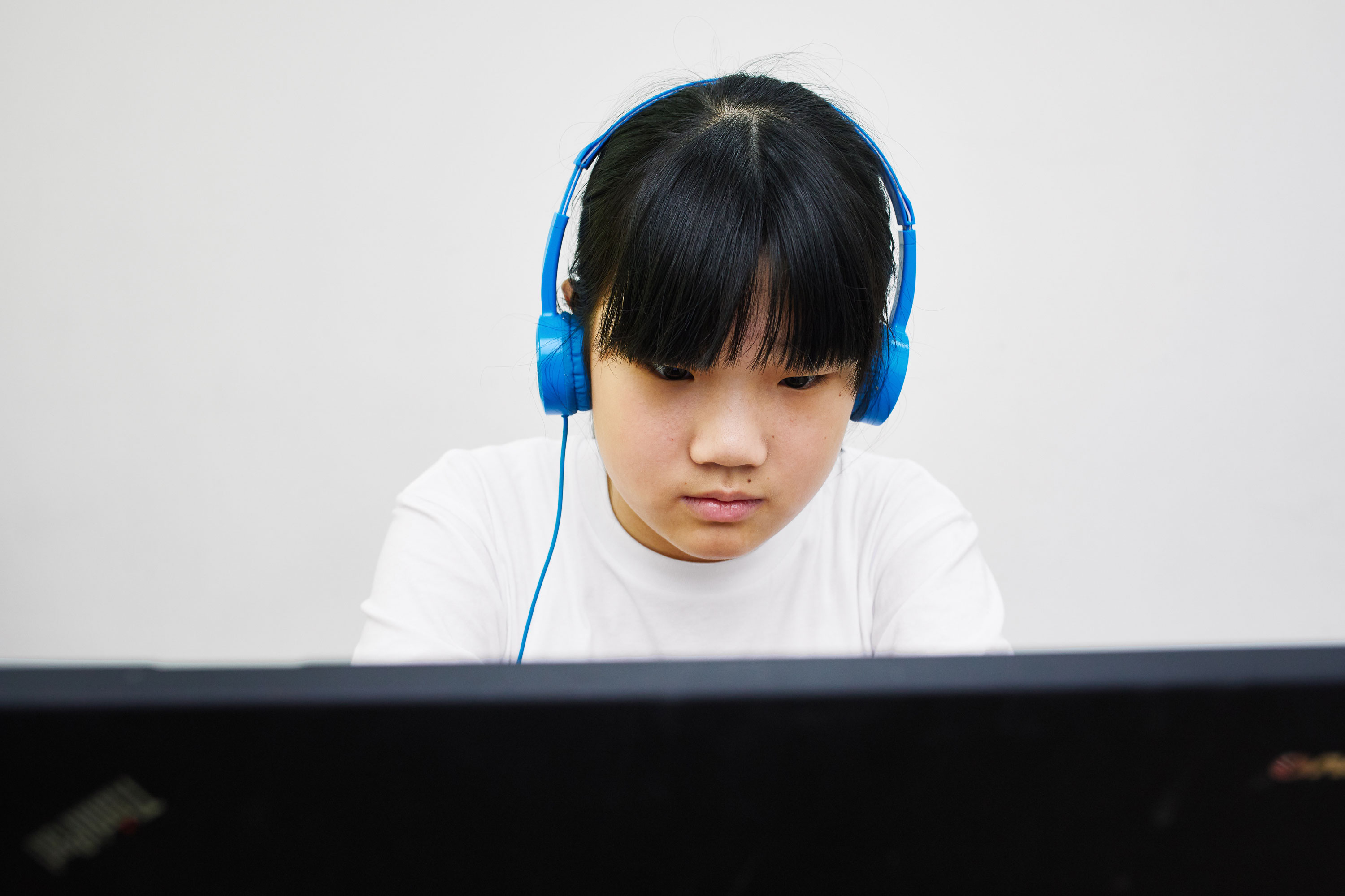 Student wearing headphones and looking at a computer monitor