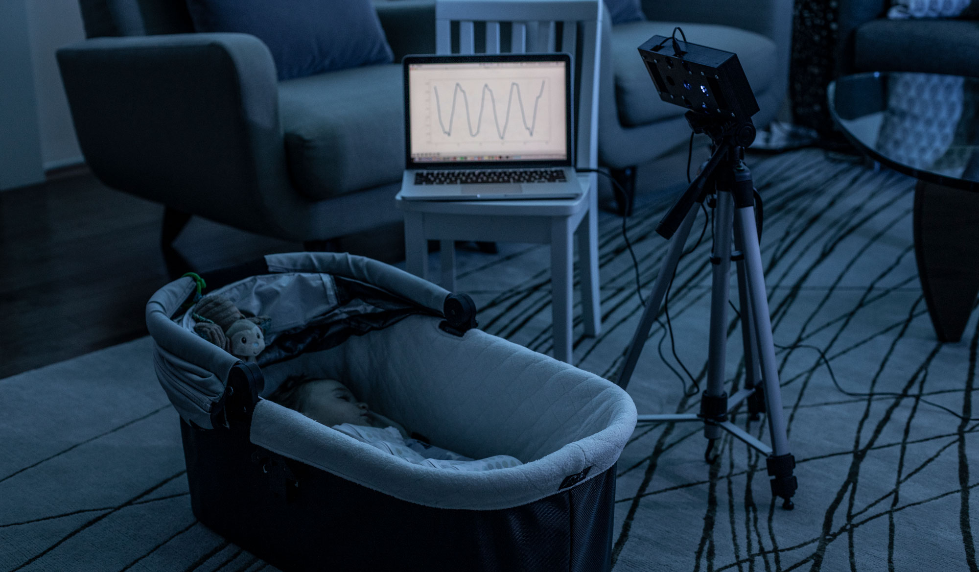 A baby sleeping in a cot has their breathing monitored remotely