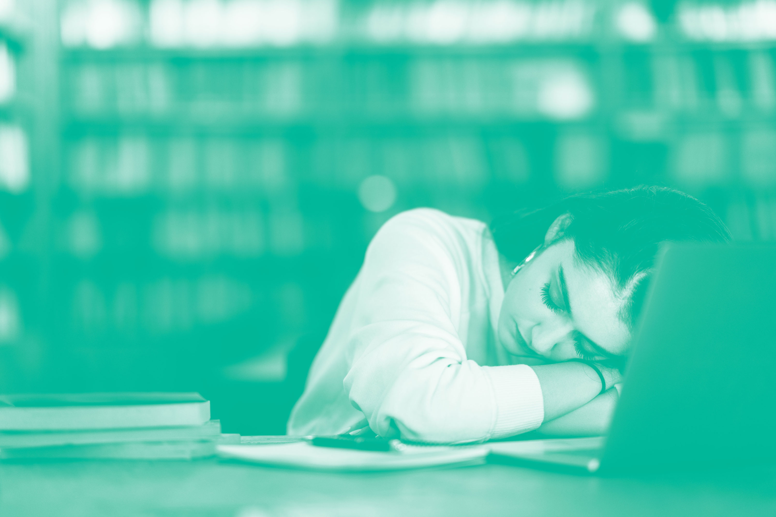 A woman sleeping by books and a laptop