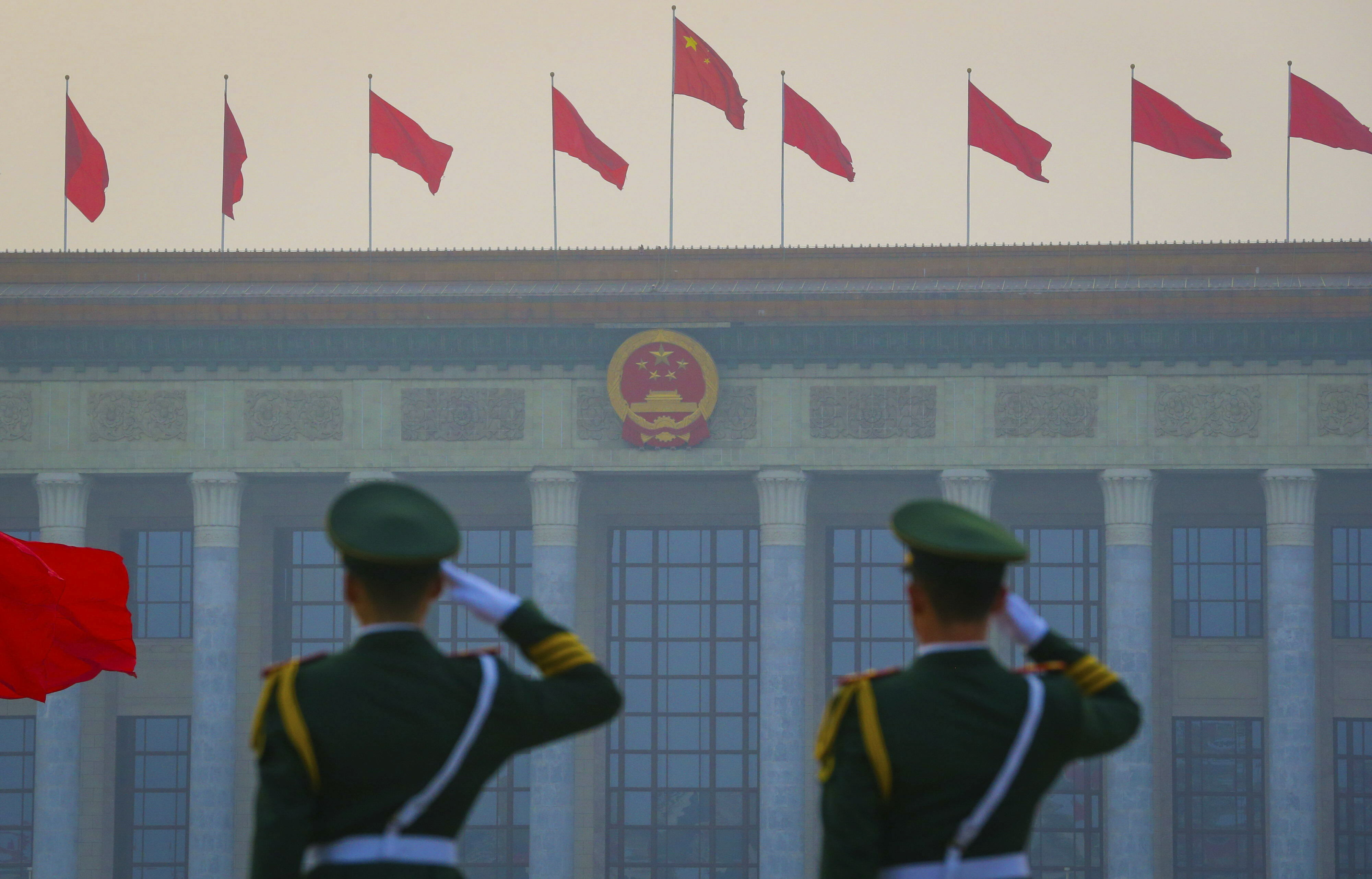 Chinese paramilitary armed policemen salute as red flags flutter in front of the Great Hall of the People in Beijing.