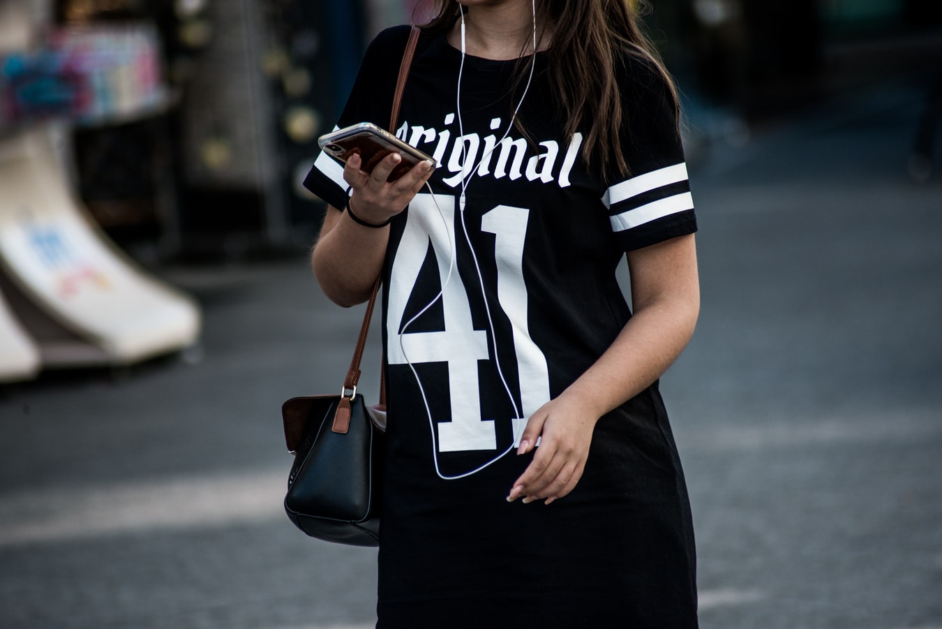 woman walking with iphone smartphone cell phone distracted texting app on street