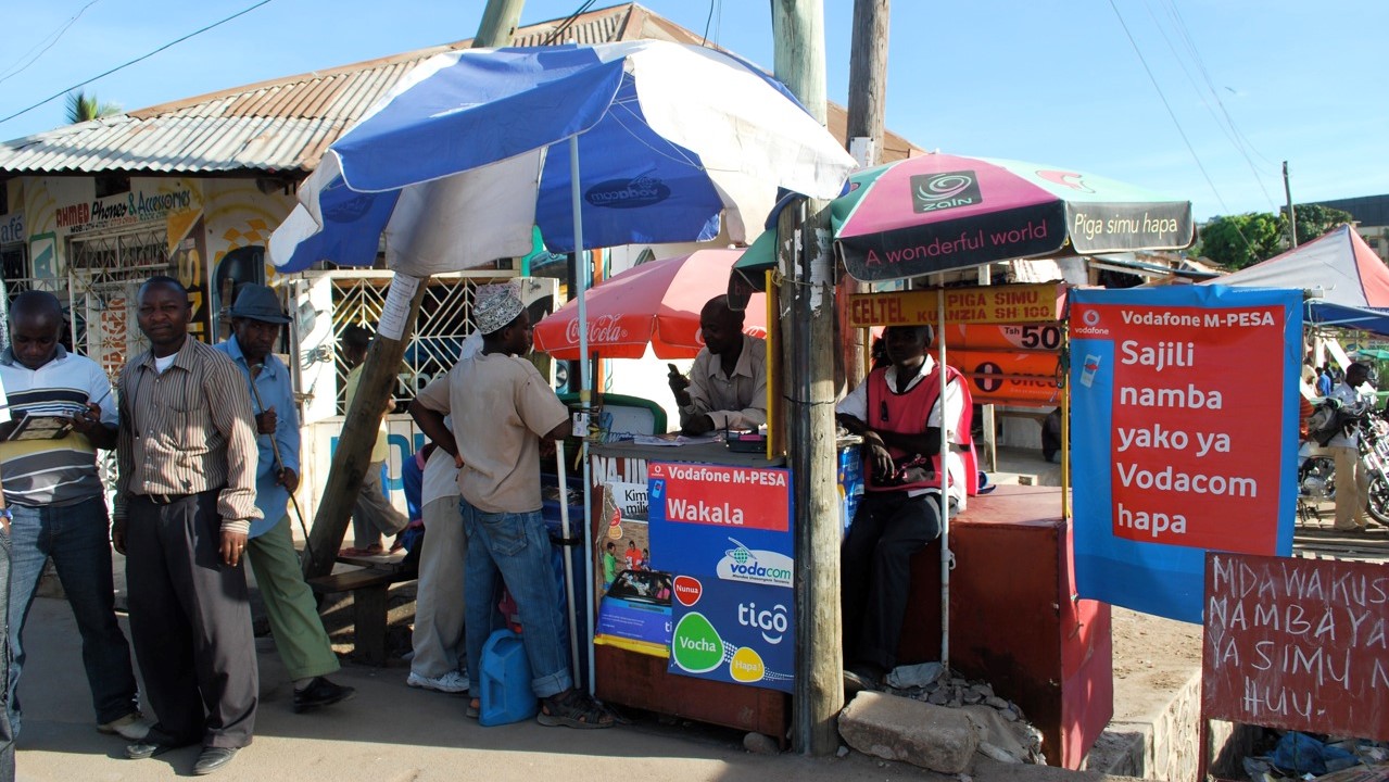 A street vendor in Tanzania with signs showing that they accept Vodafone&#039;s M-Pesa digital payment system.