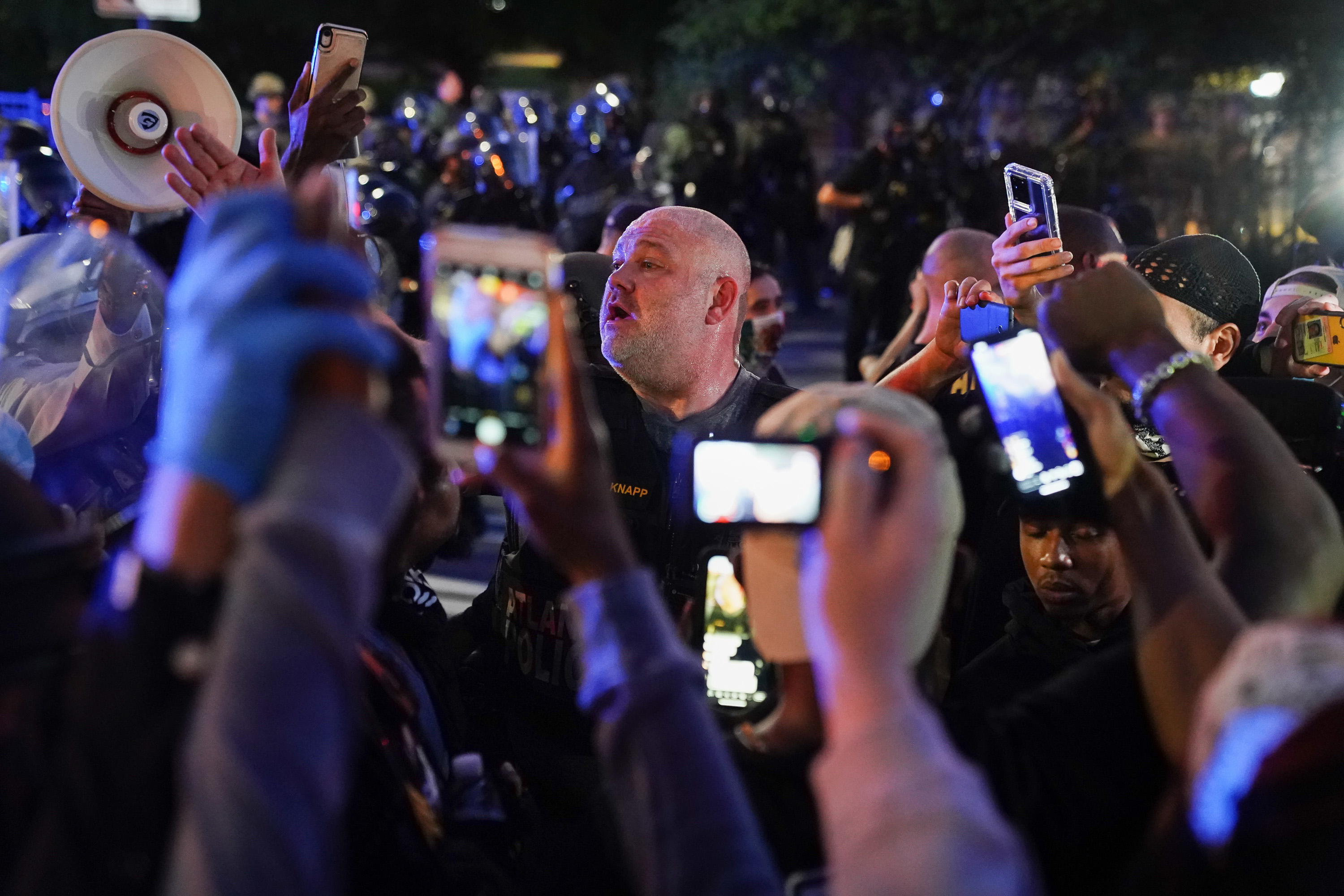 People in a crowd filming at night with cellphone cameras