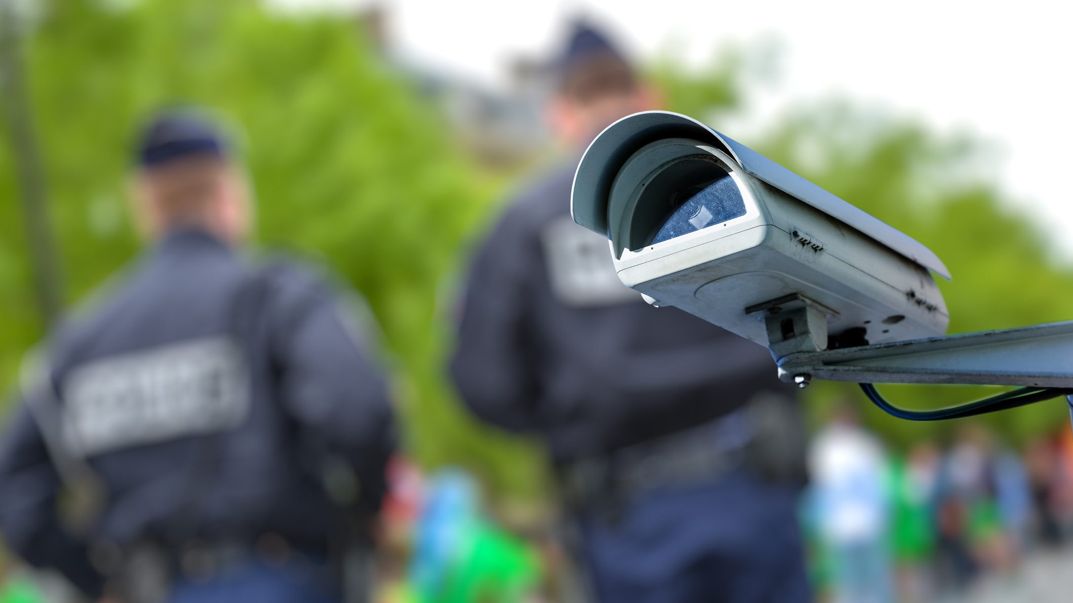 Focus on security CCTV camera or surveillance system with police officers on blurry background