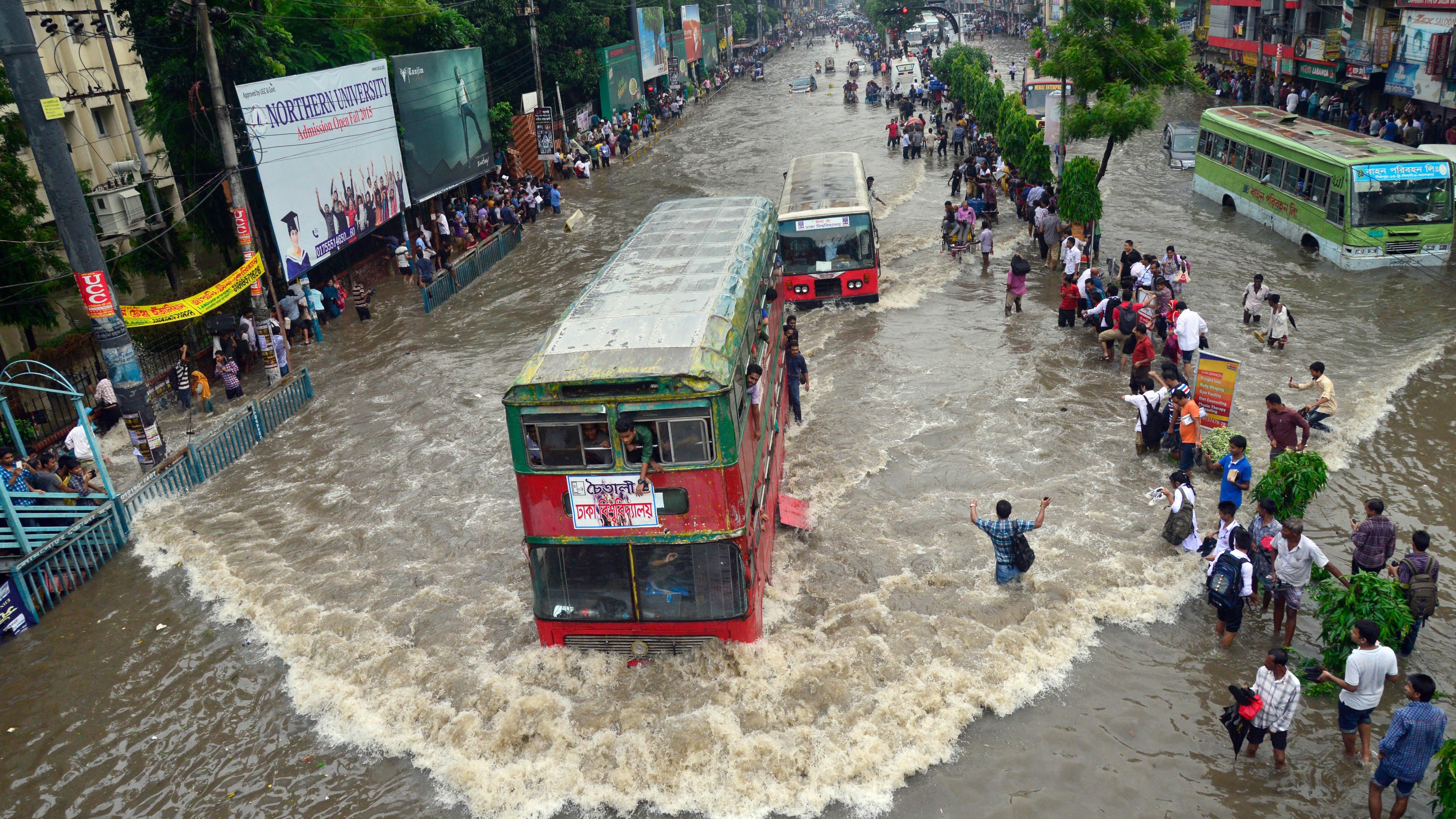 Vehicles try driving through the flooded Dhaka streets