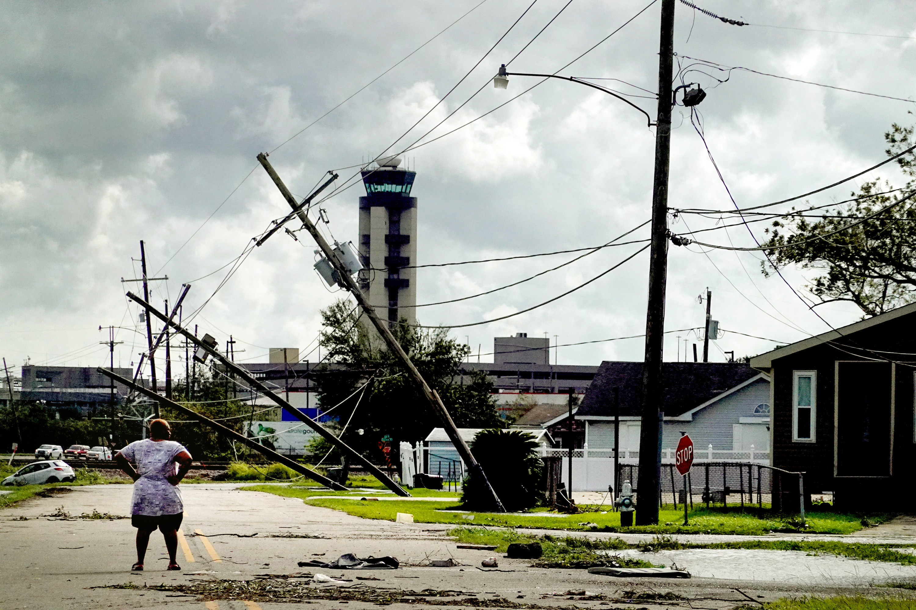 woman looks over damage to a neighborhood caused by Hurricane Ida