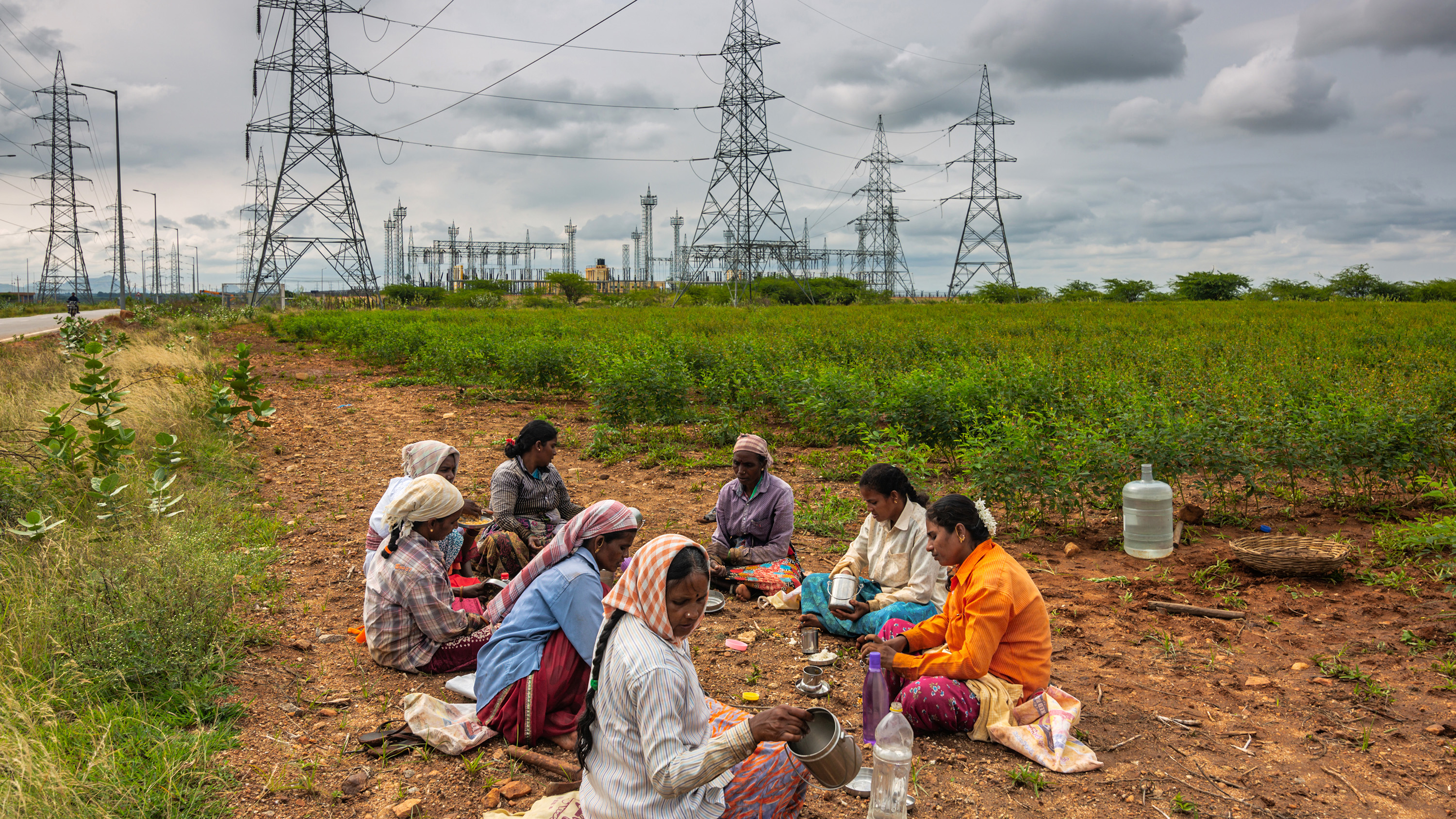 Women eat their breakfast under electric pylons built to transfer electricity generated at the Pavagada Solar Park