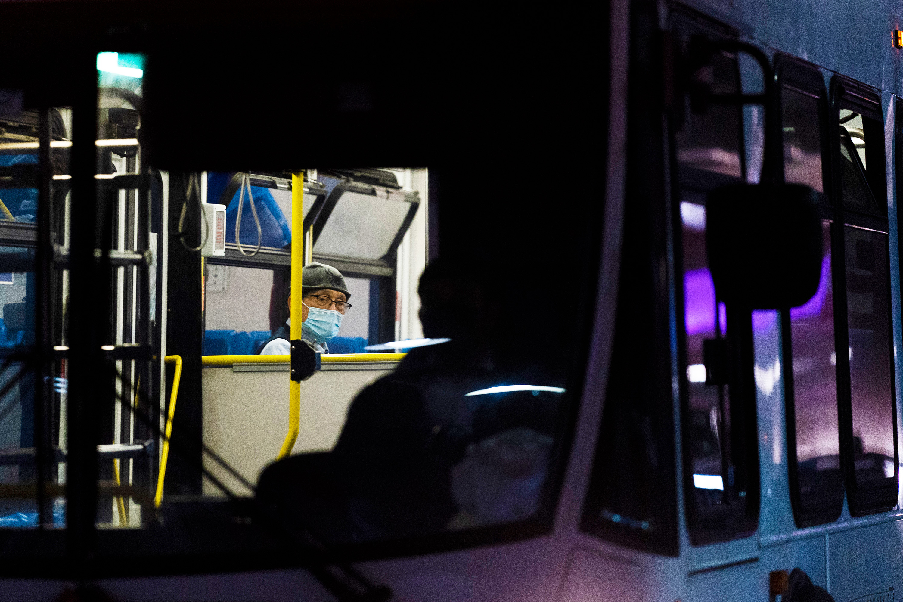 A traveler wearing a protective face mask sits in a shuttle bus at the Los Angeles International Airport
