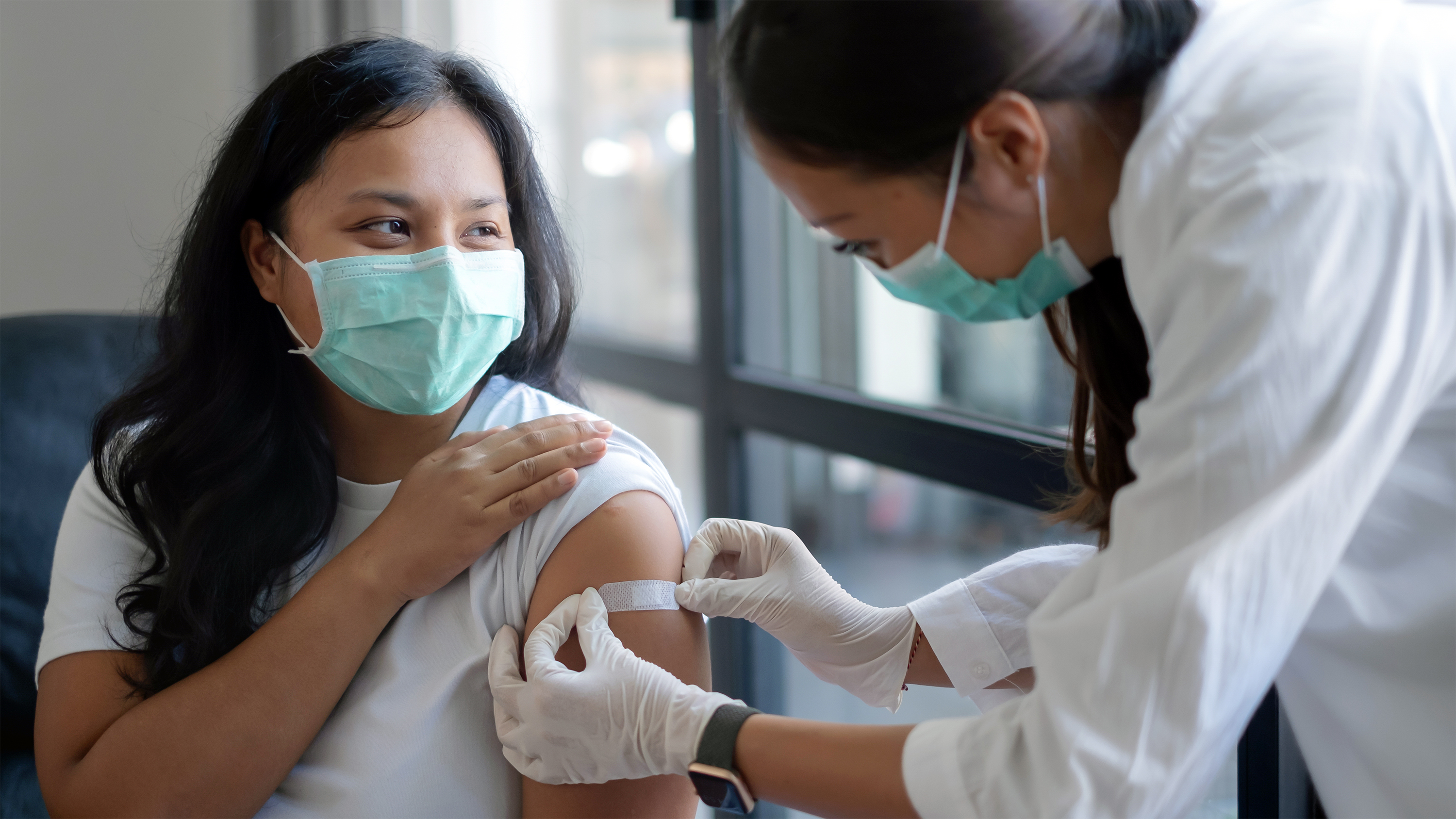 healthcare worker putting adhesive bandage to patient&#039;s arm