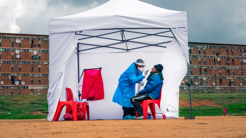 A tent outside with a healthcare professional performing a COVID test on a patient. AP PHOTO/JEROME DELAY
