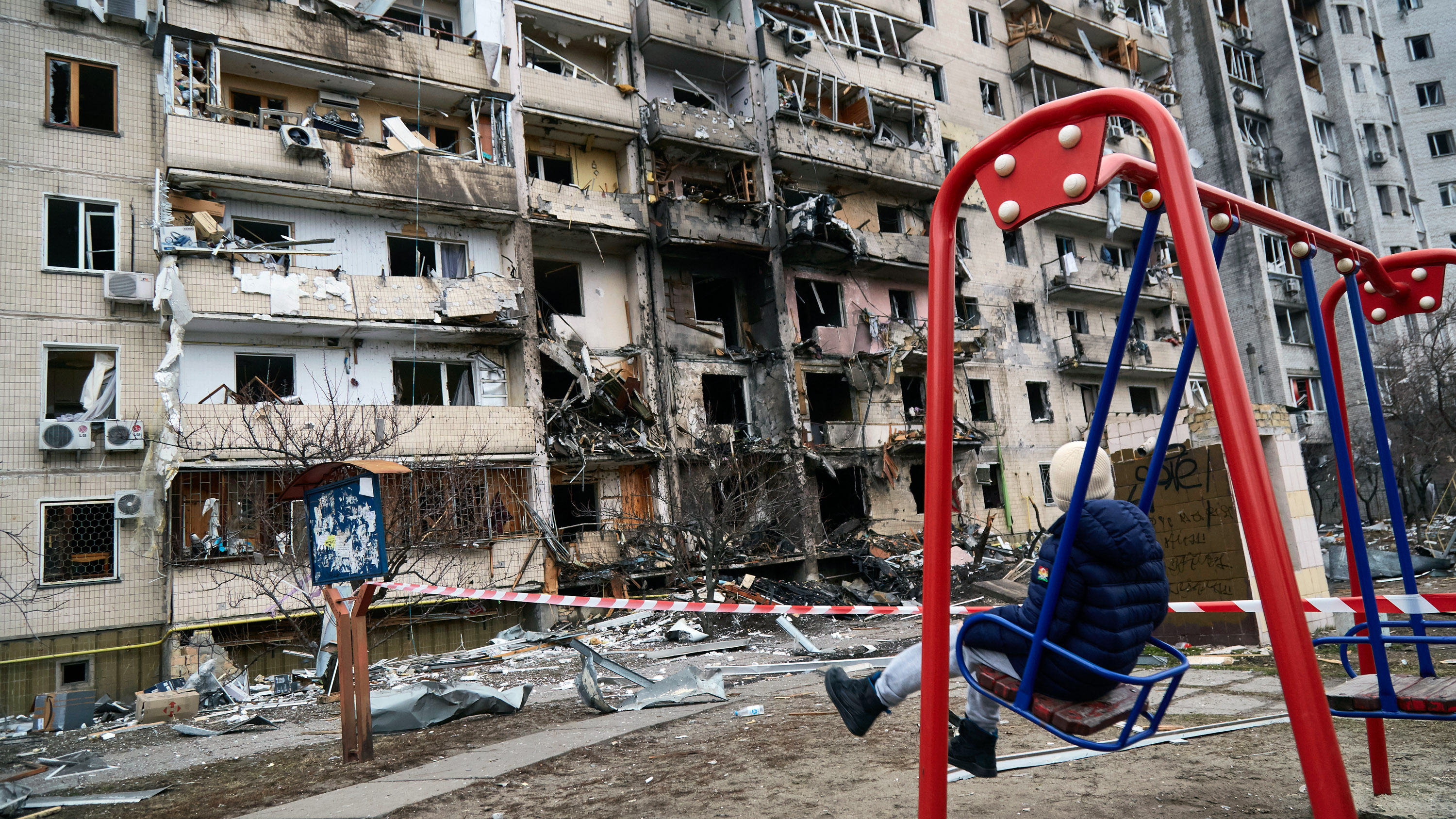 child outside a destroyed residential building in Kiev