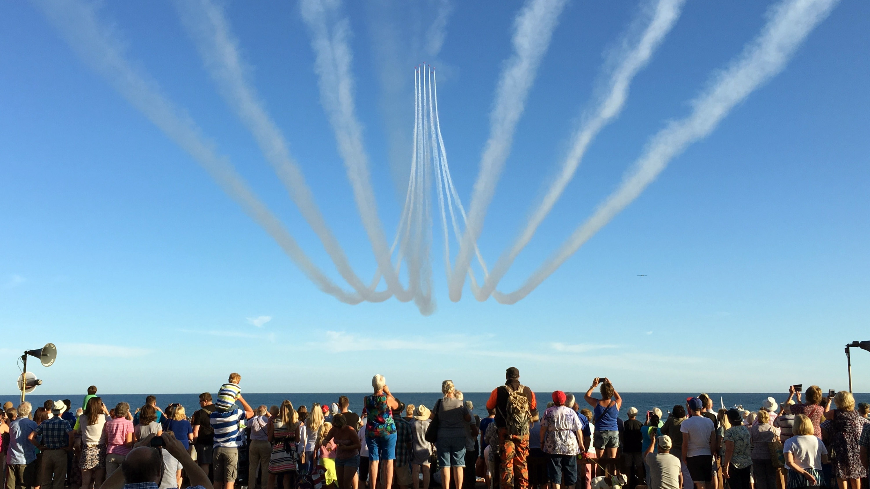 Crowd watches formation of planes flying above