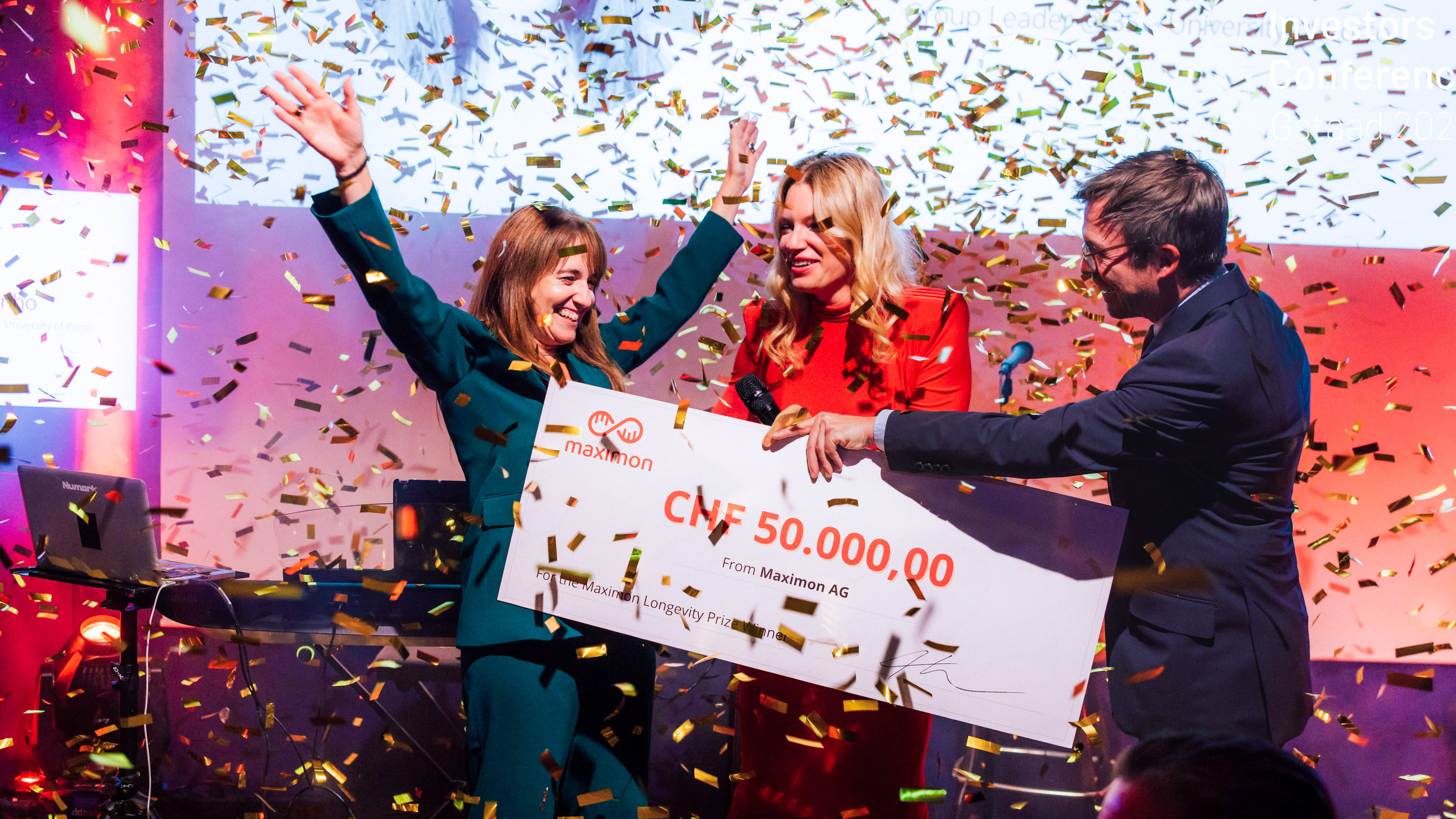 Longevity Prize winner celebrates with raised arms as confetti falls and she receives an oversized check