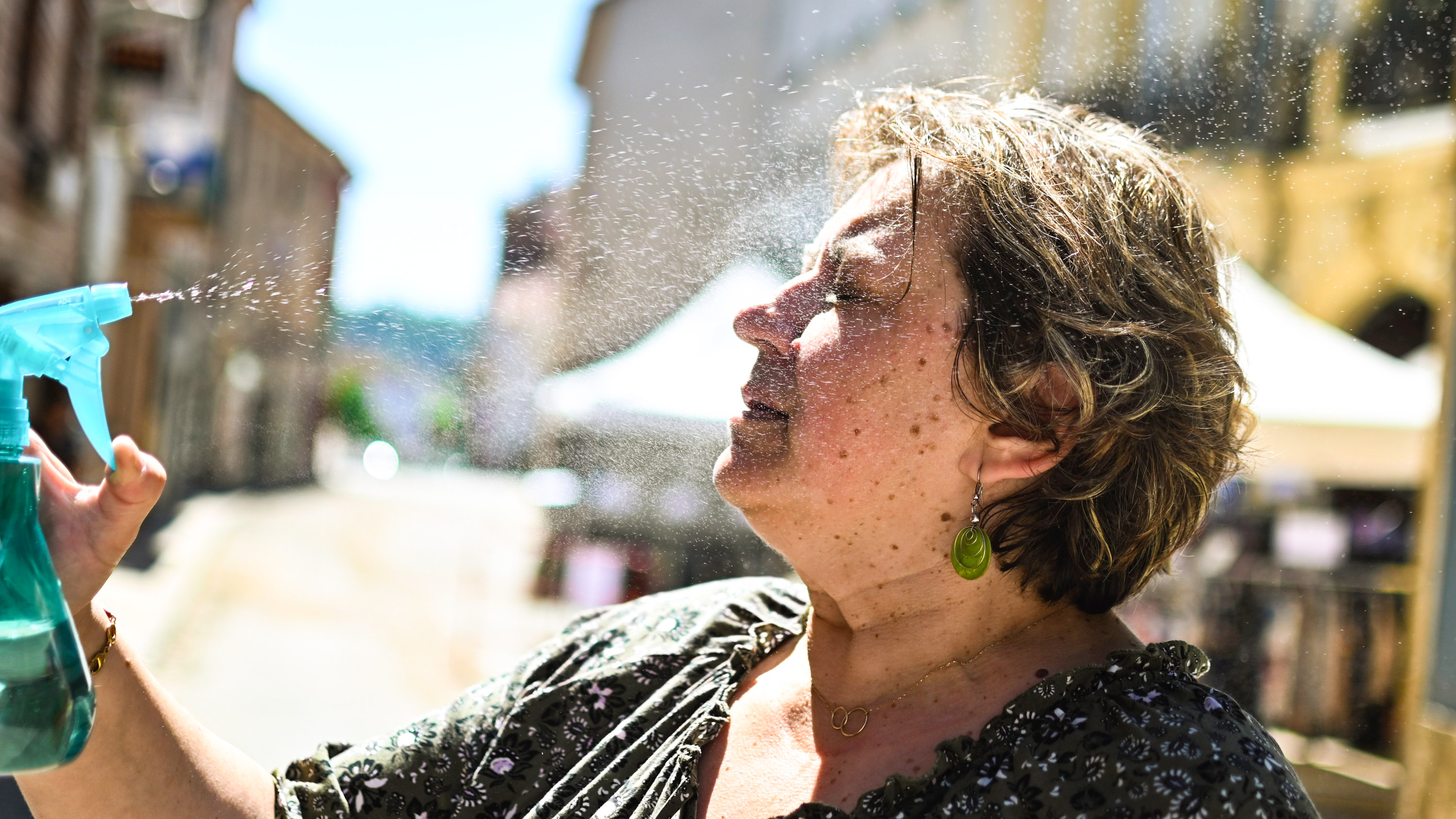 A woman sprays herself with water to cool down.