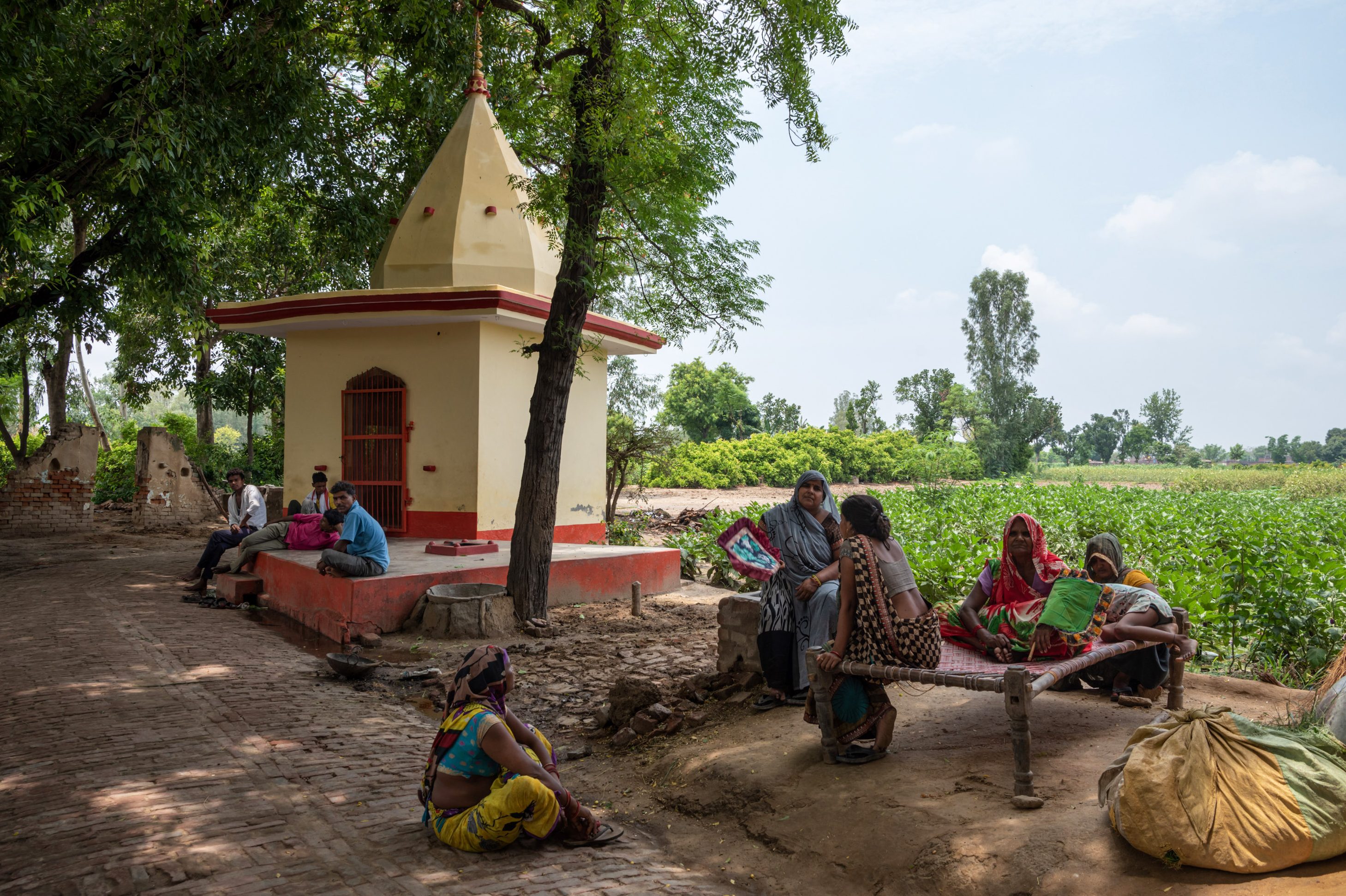يجلس الناس تحت شجرة بانيان بجوار المعبد هربًا من الحرارة.