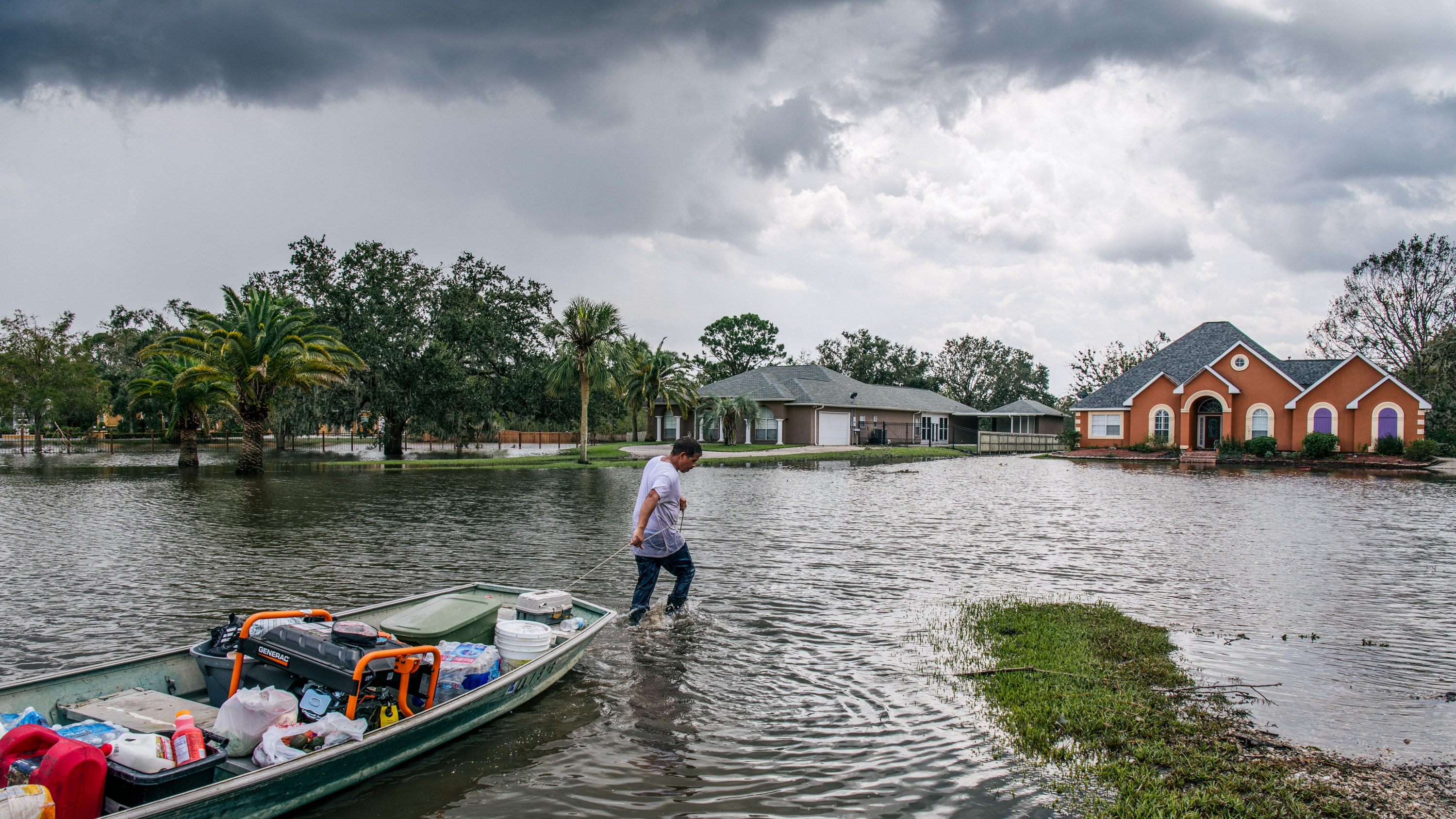 Un hombre tira de un bote a través de un barrio inundado