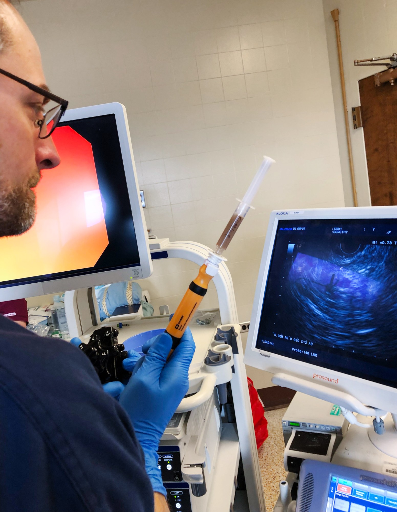 researcher holding a syringe and observing an ultrasound machine