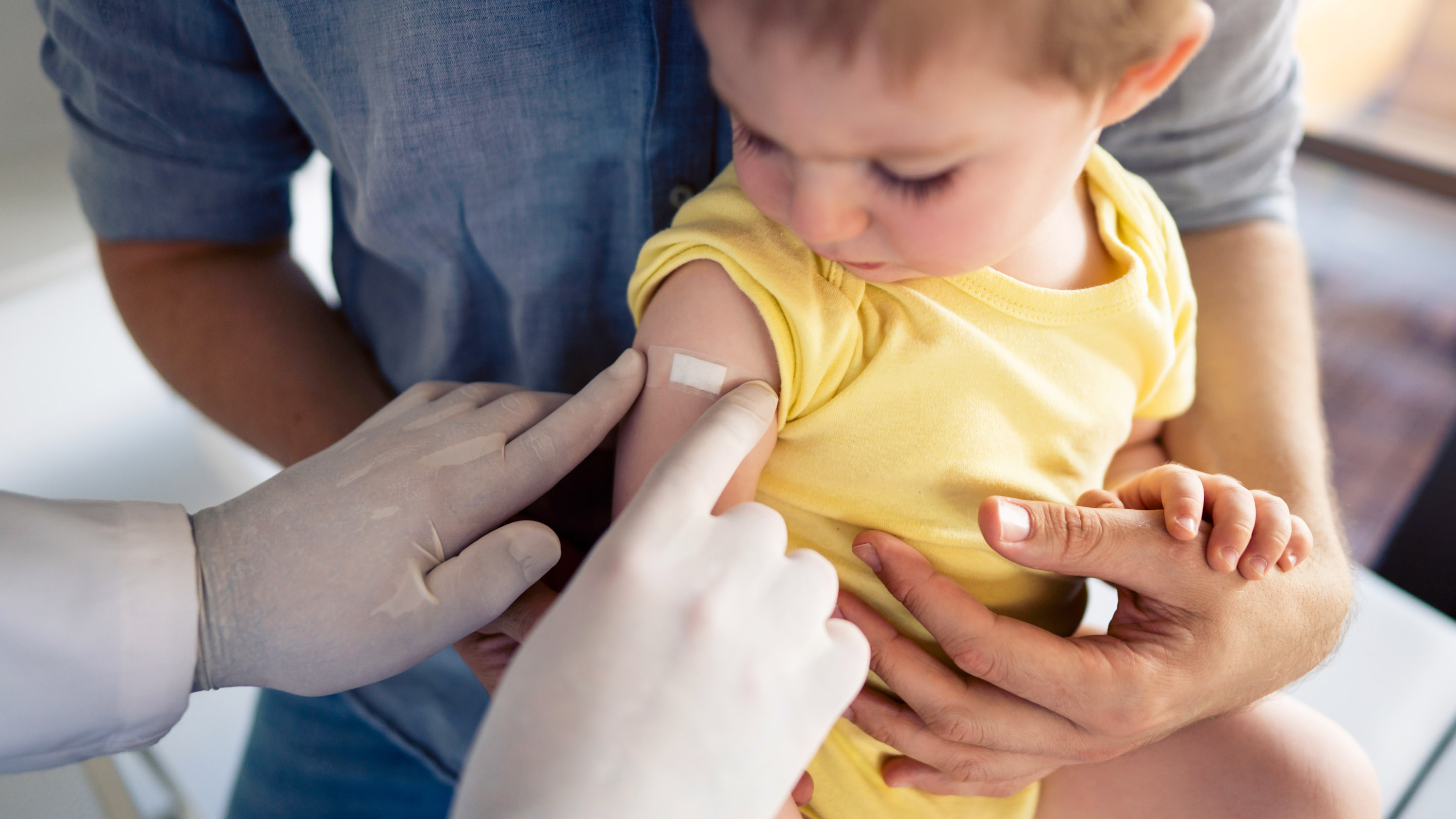 One unrecognizable doctor putting a patch on child&#039;s shoulder after successful vaccination