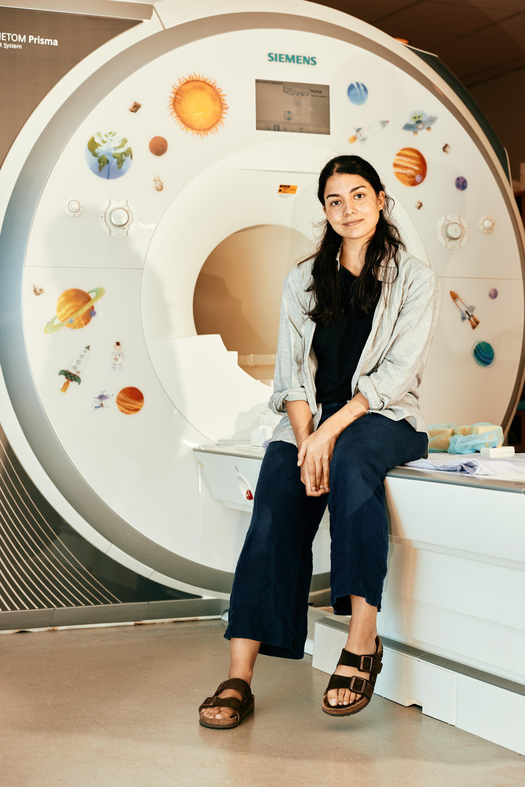 Saima Malik-Moraleda sitting on the edge of the MRI