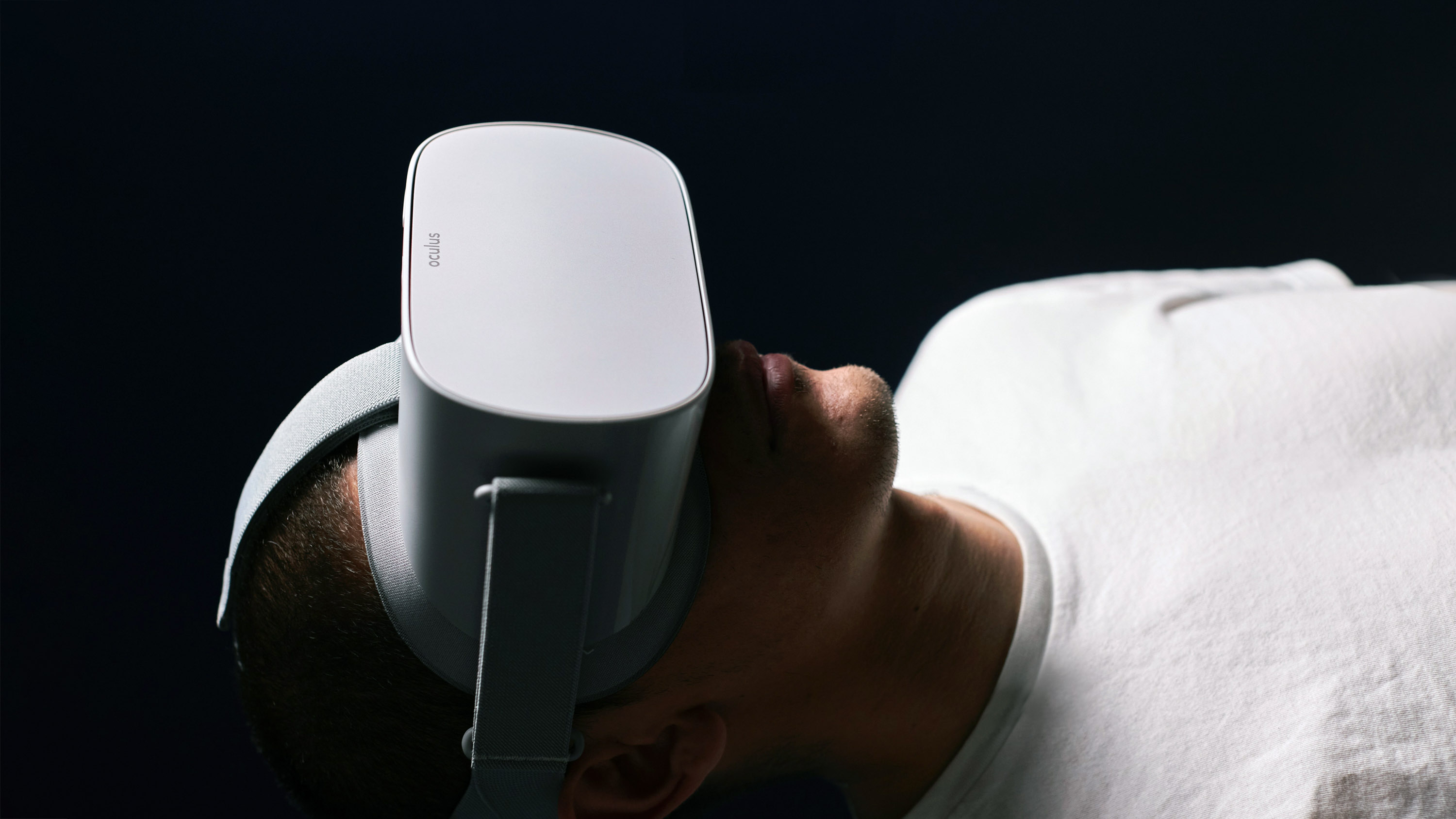person laying down in a dark room wearing an Oculus headset