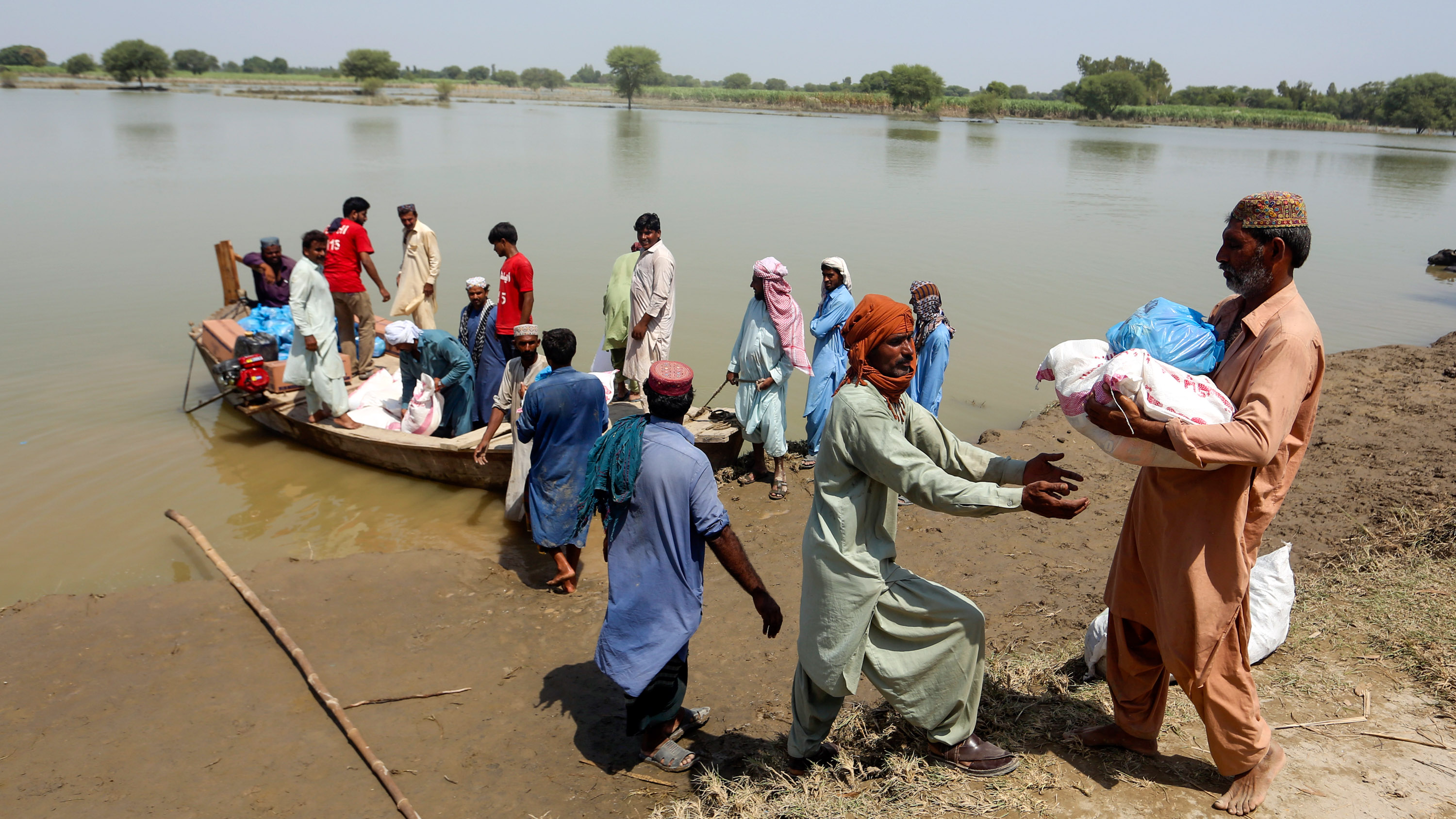 flooding victims and relief workers load aid onto a small boat in Pakistan