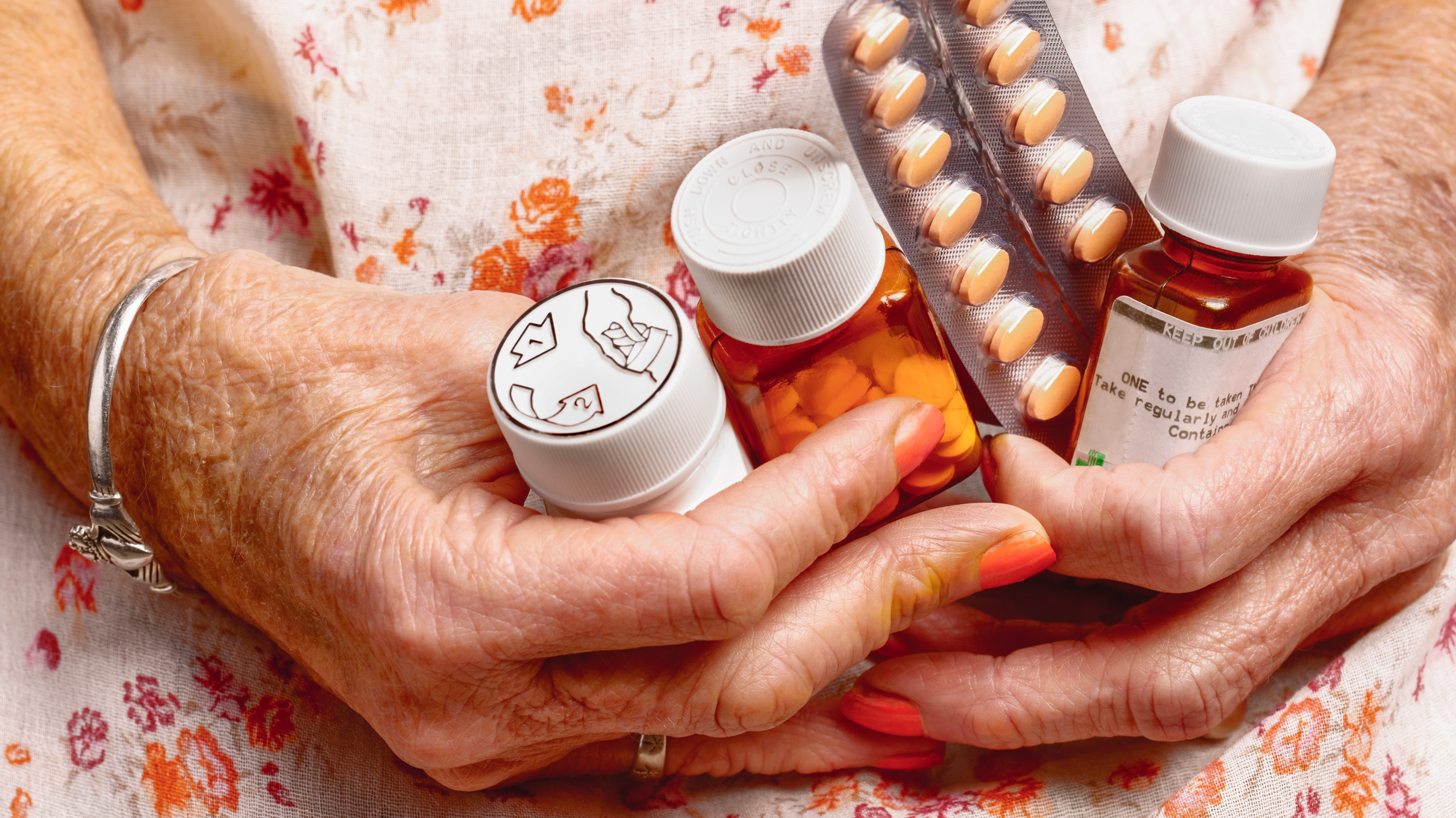 elderly woman&#039;s hands holding multiple prescription medications