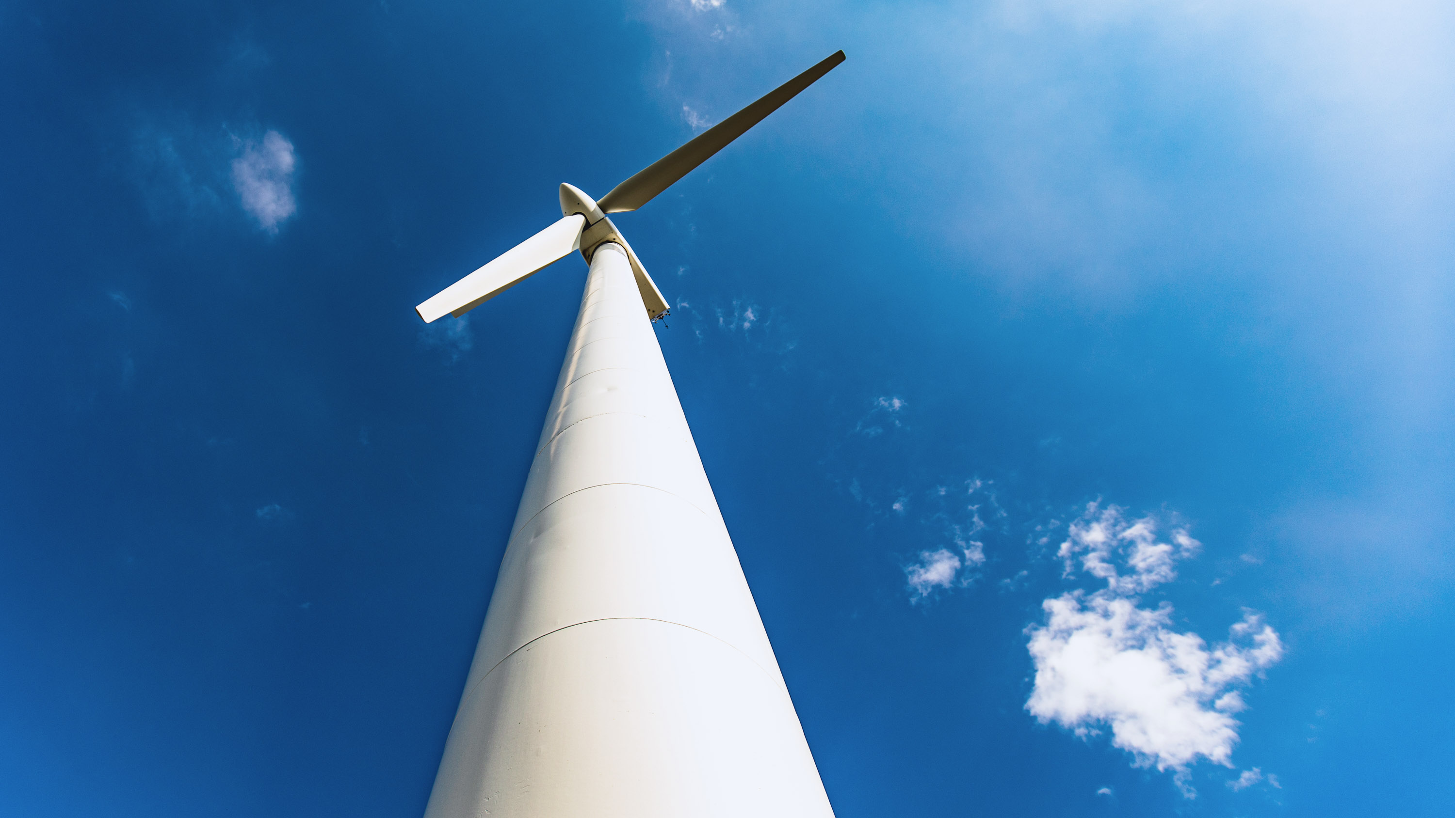 A large wind turbine seen from below set against a blue sky.