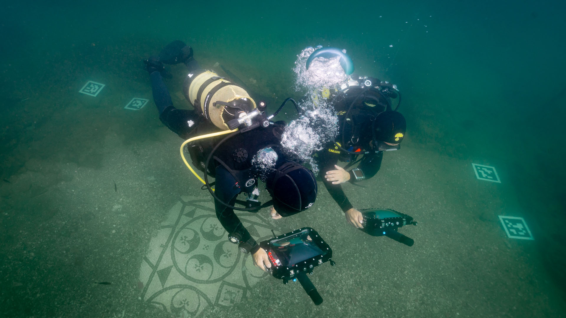 two divers holding portable monitors underwater