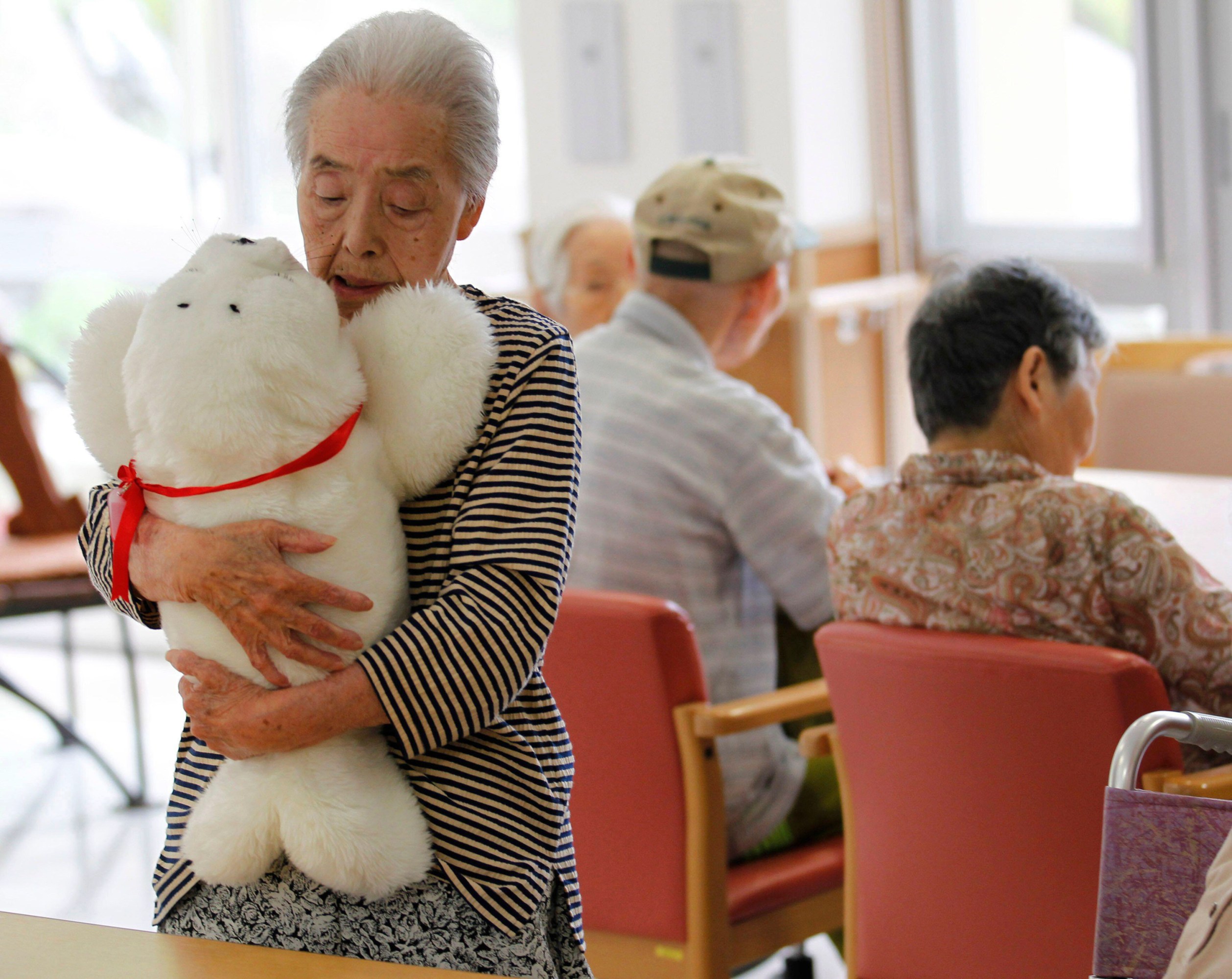 Satsuko Yatsuzaka (84) holds a therapy robot called Paro at the Suisyoen Nursing Home.
