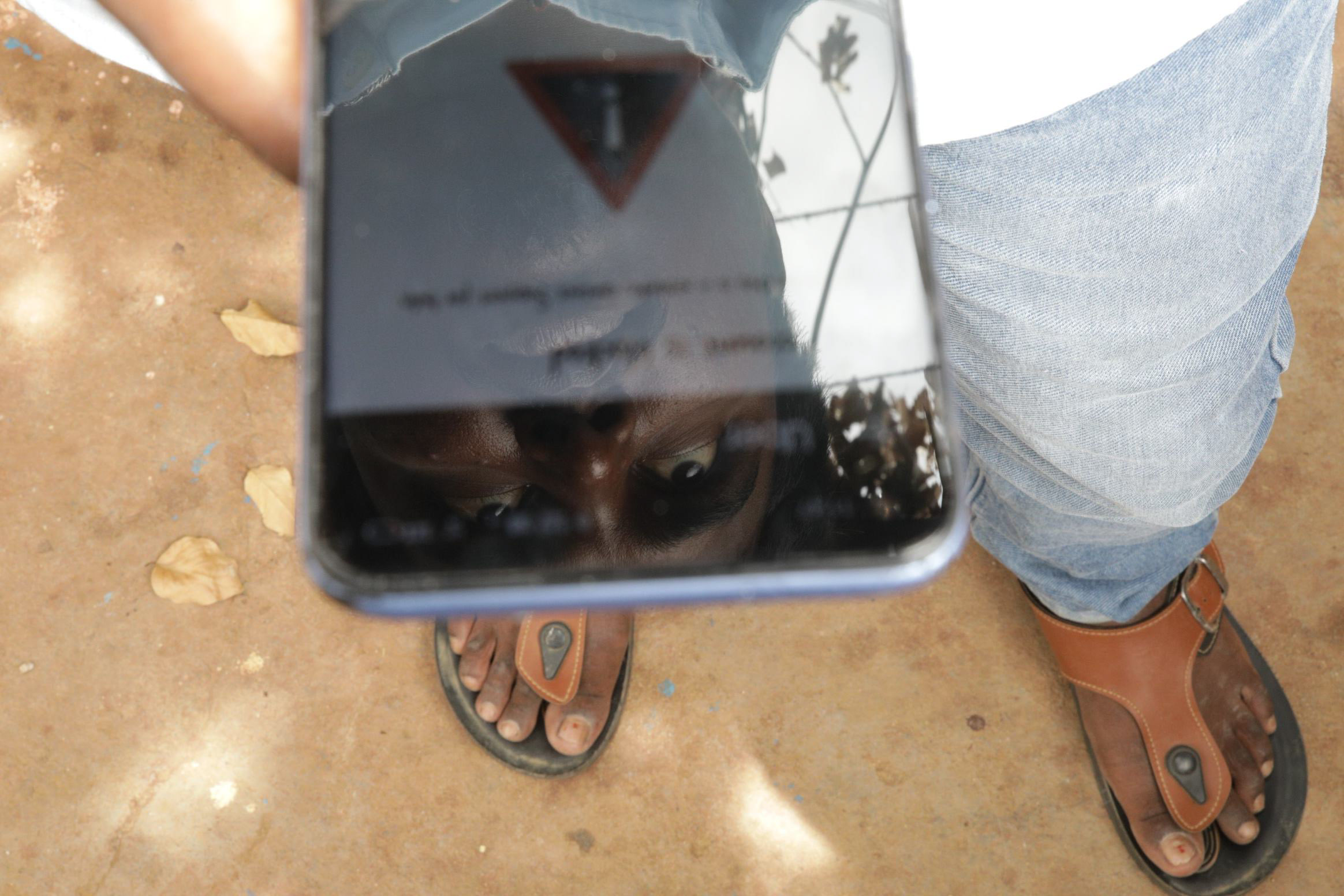 Srikanth's face reflected in his phone screen, which is on the lockout message from Uber