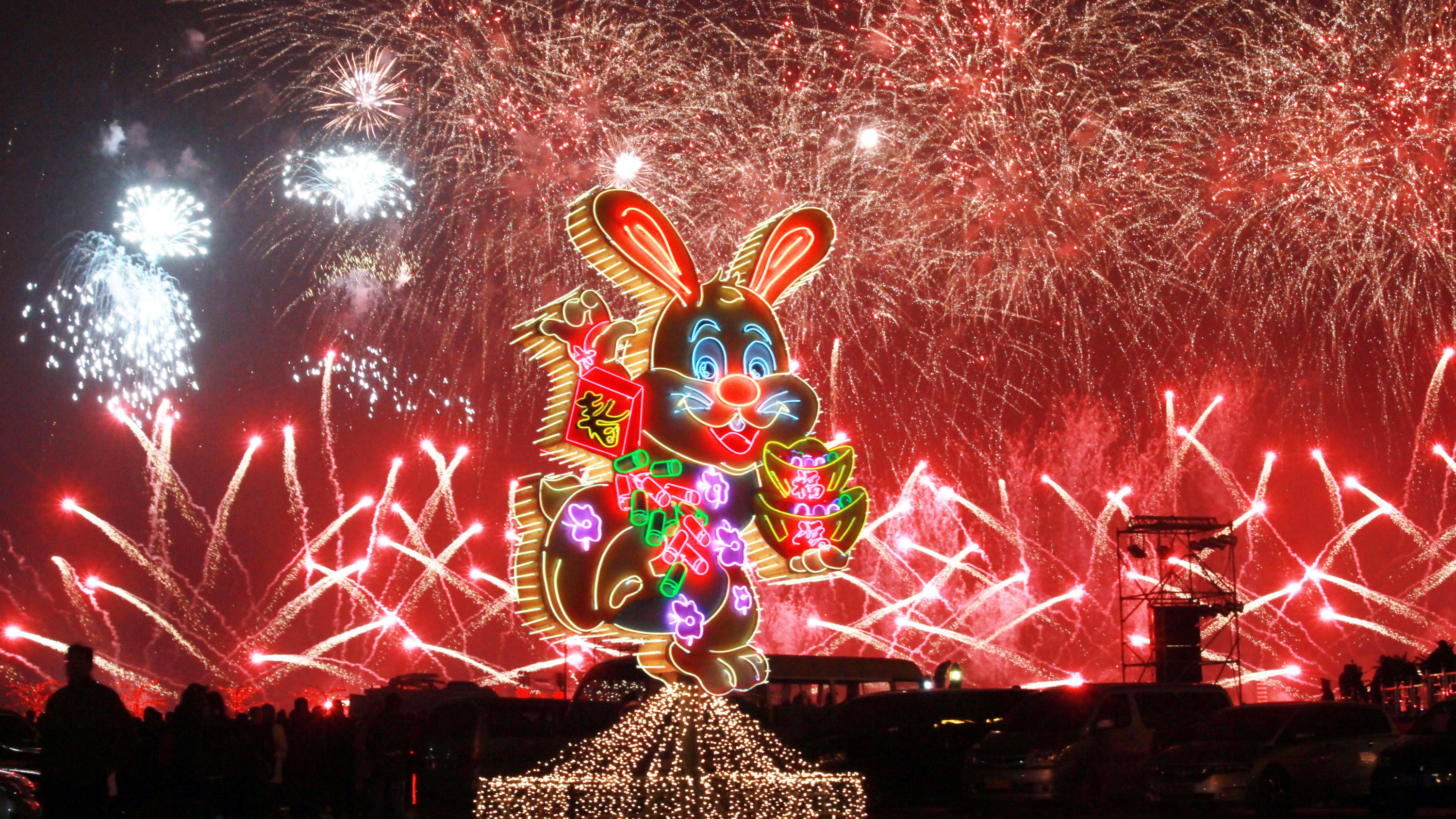 Fireworks are seen behind a neon-light rabbit in Dalian, China