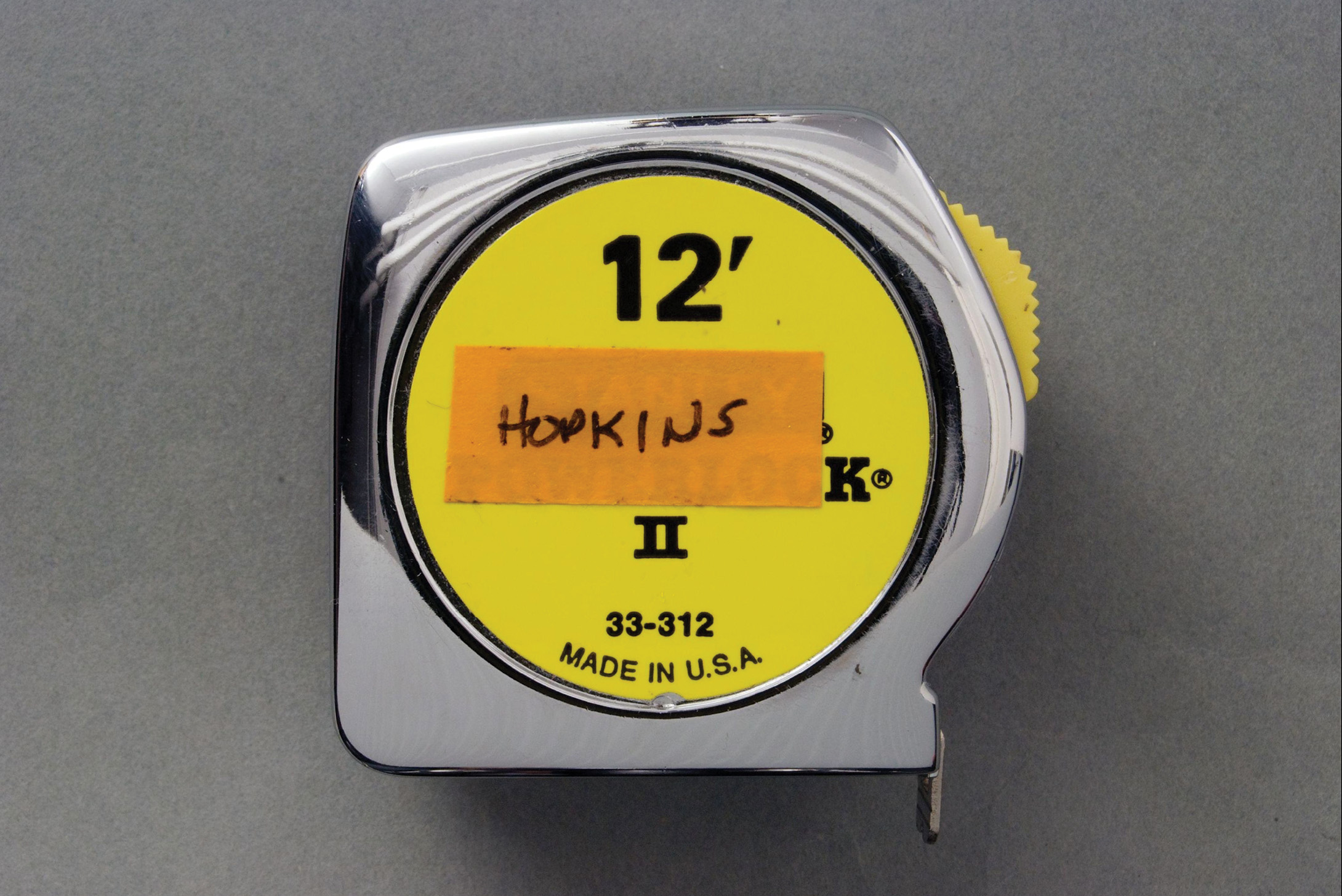 Metal retractable measuring tape with a yellow label reading, 