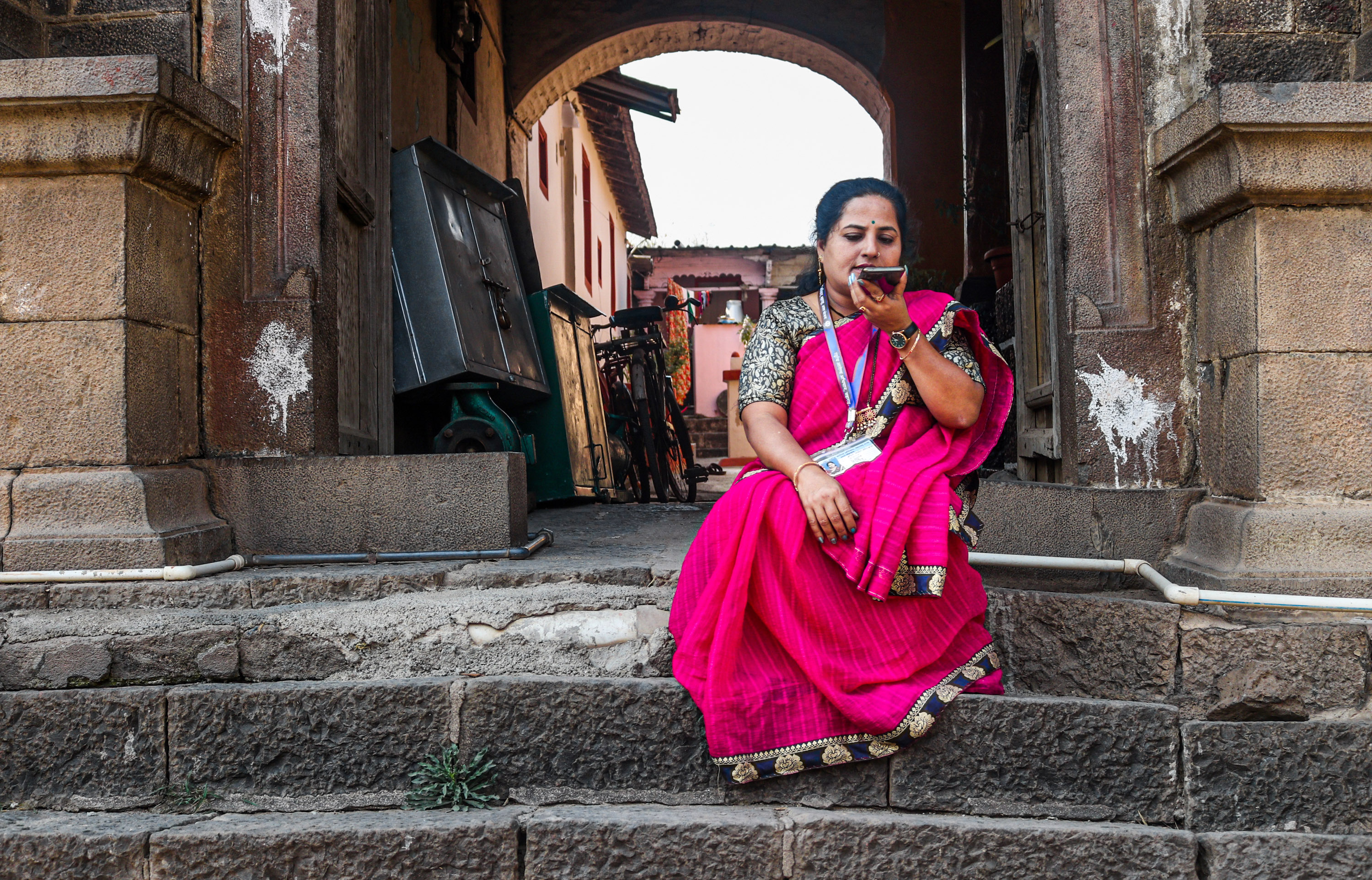Netradipa Patil sits on steps and speaks audio notes into her cell phone