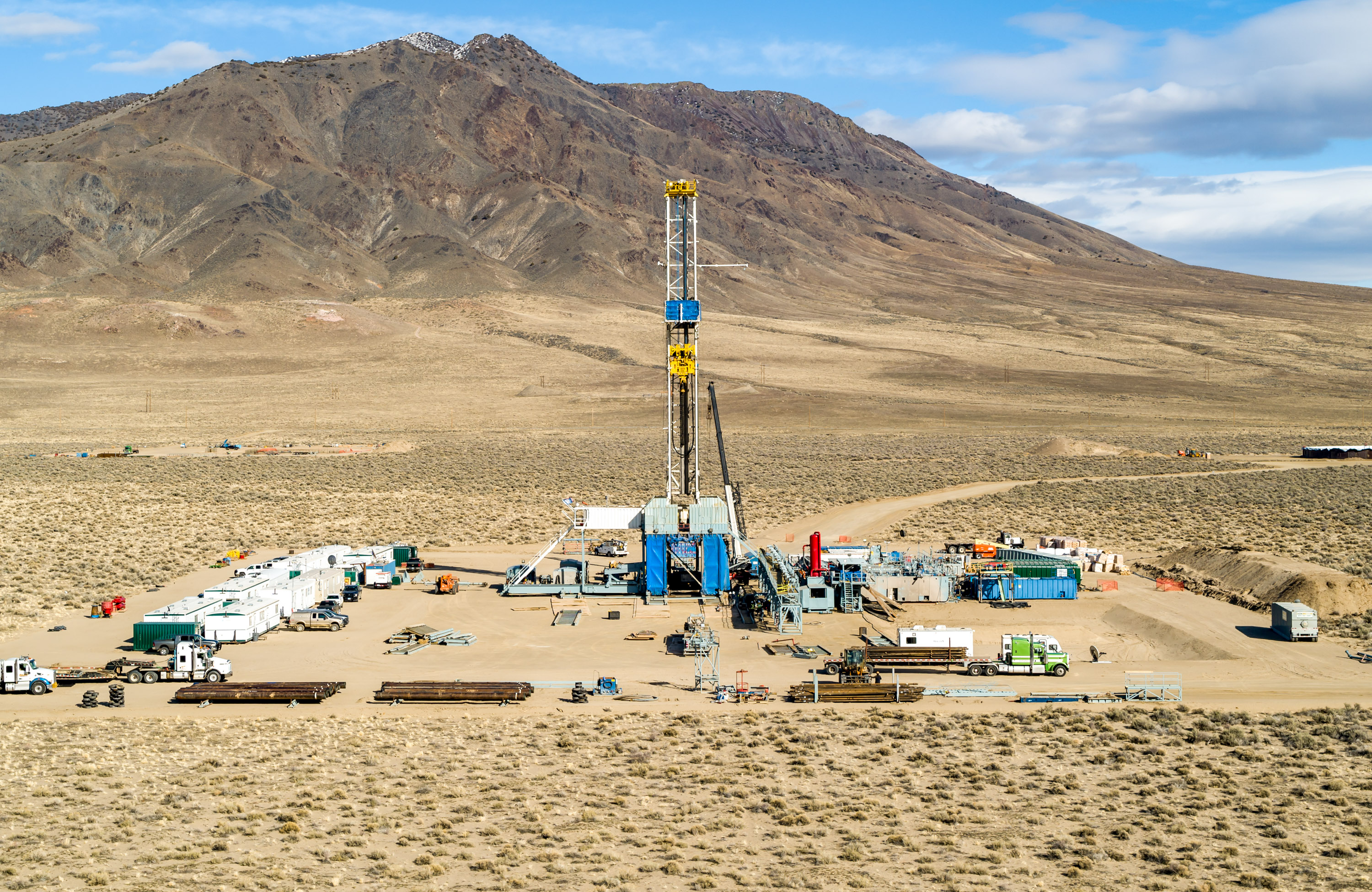 An elevated view of the Fervo drilling operation in Nevada with mountain in the distance.