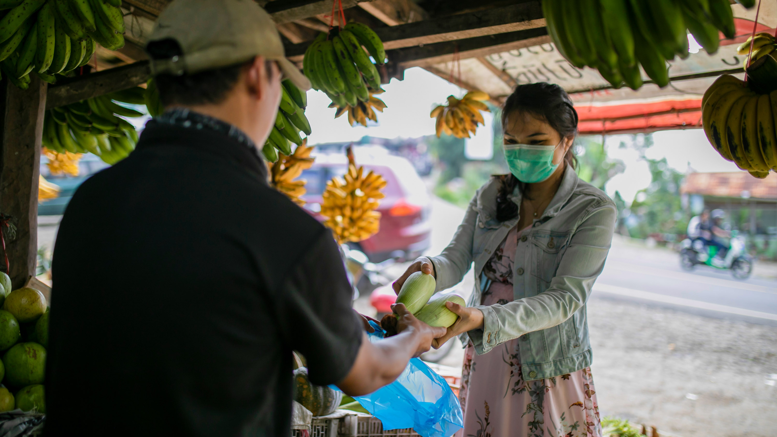 Masked woman buying fruit at an open air market in Indonesia