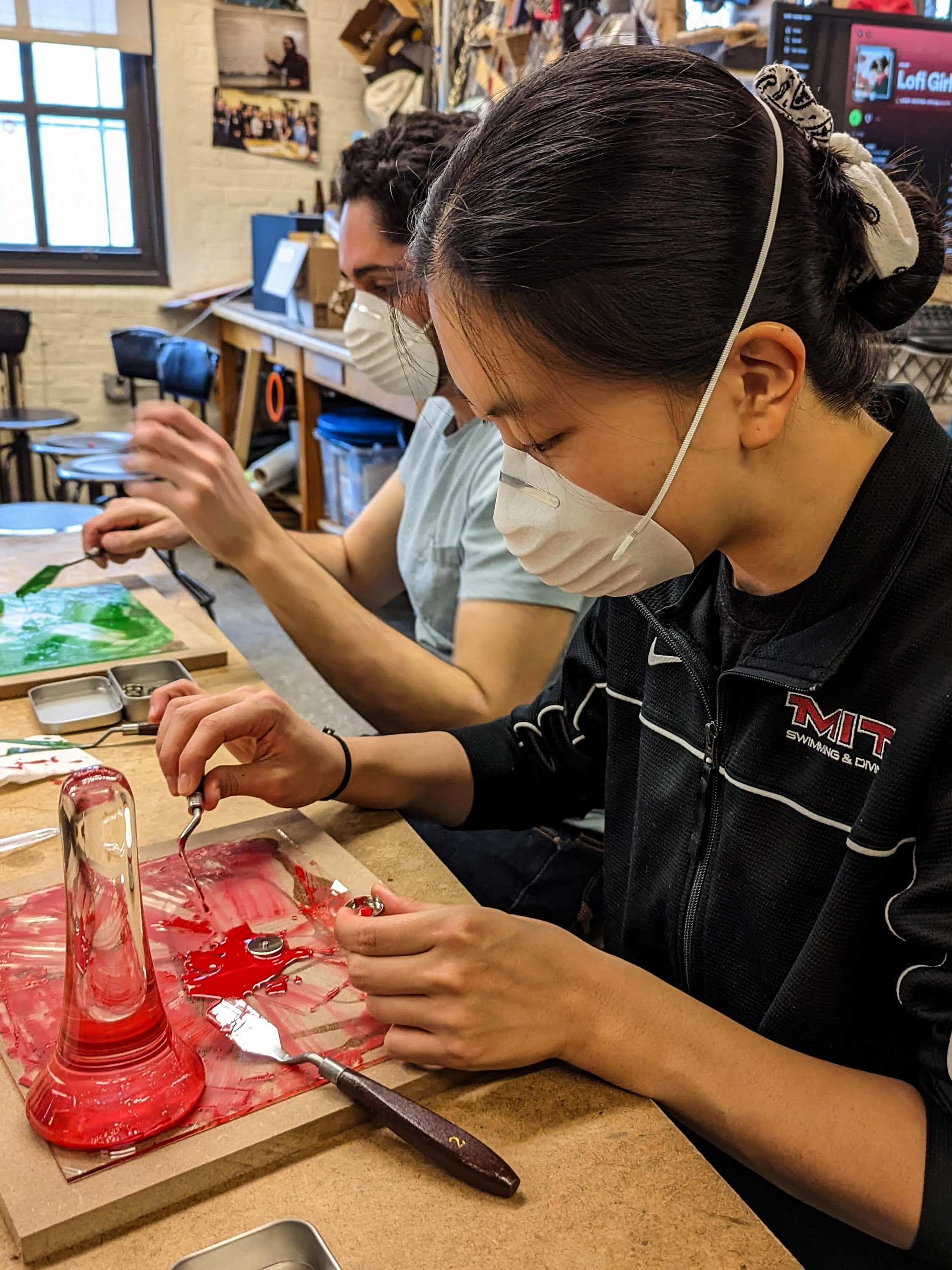 MIT students using palette knives to move paint on a glass plate