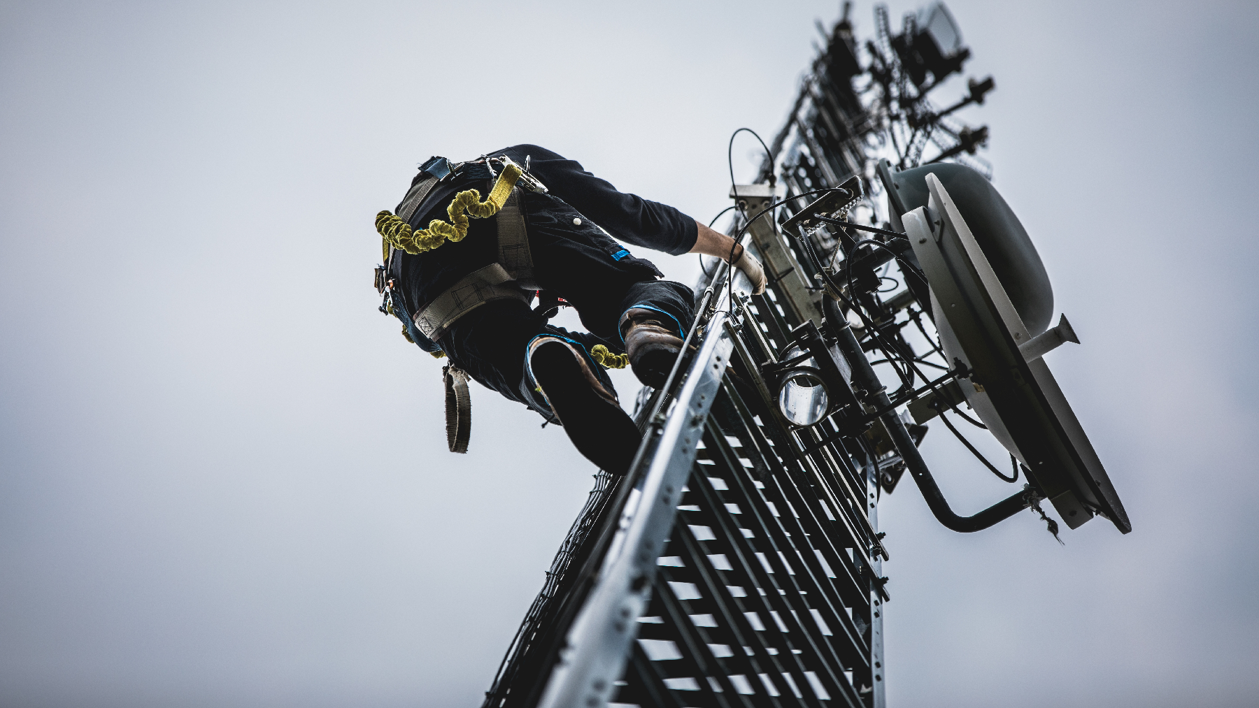 stock image of a telecommunications worker climbing a satellite tower.
