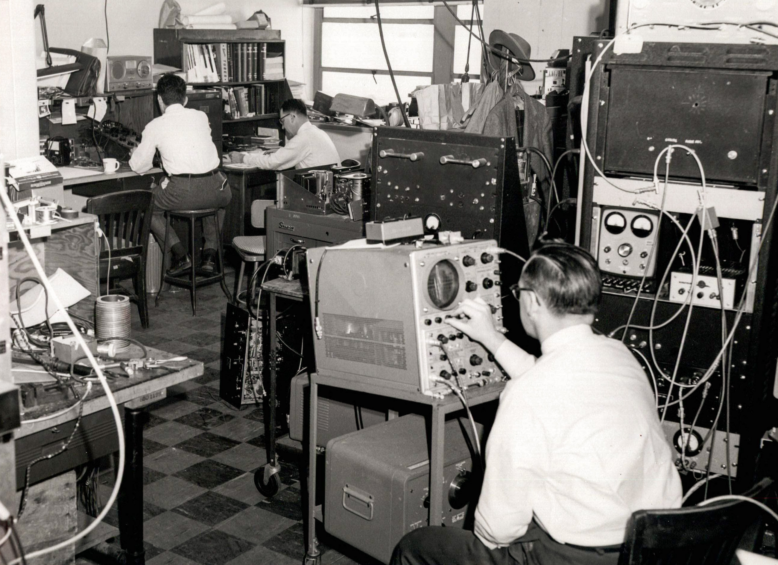 Three workers sit in front of machines