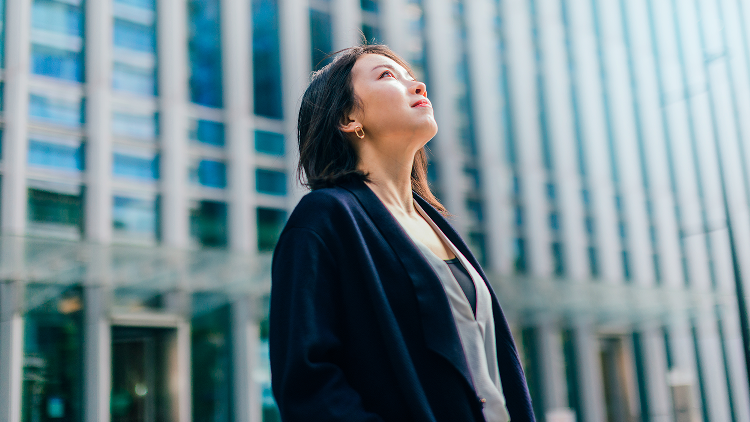 stock image of a woman in a downtown district, outdoors looking to the sky