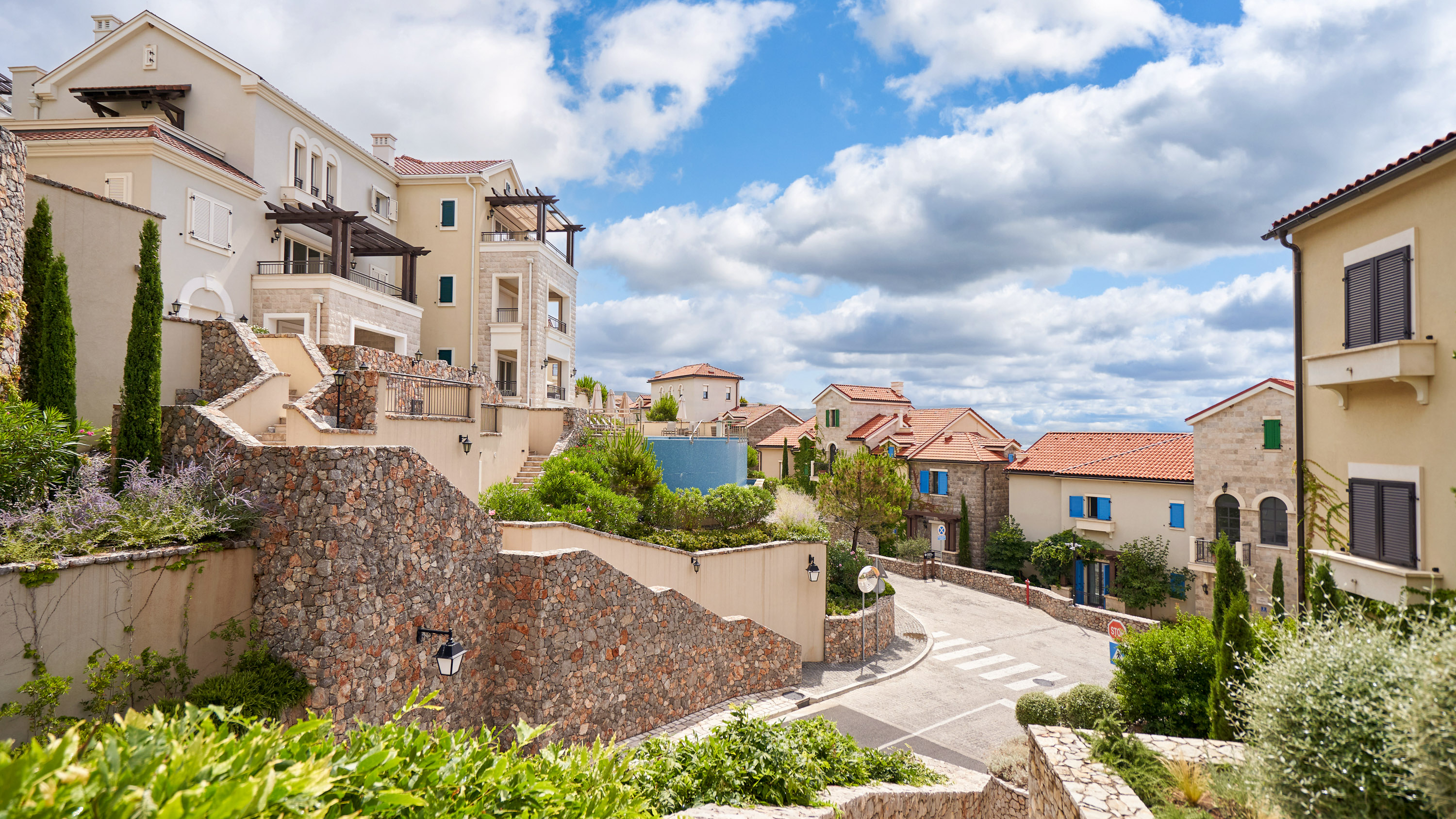 view of elevated buildings with winding stone stairways in Lustica Bay