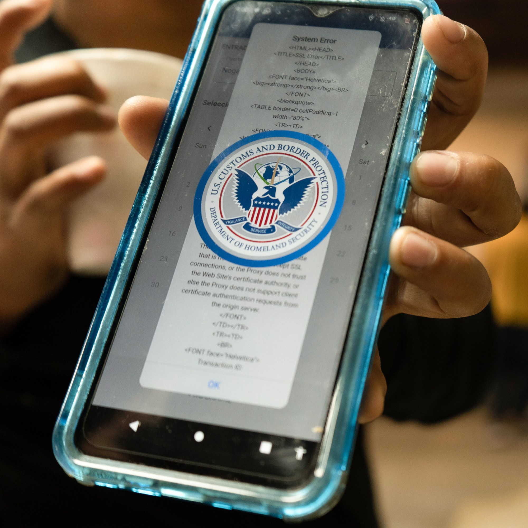 primer plano de un teléfono con el logotipo de Aduanas y Protección Fronteriza de EE. UU. visible en la pantalla sobre un código de error del sistema