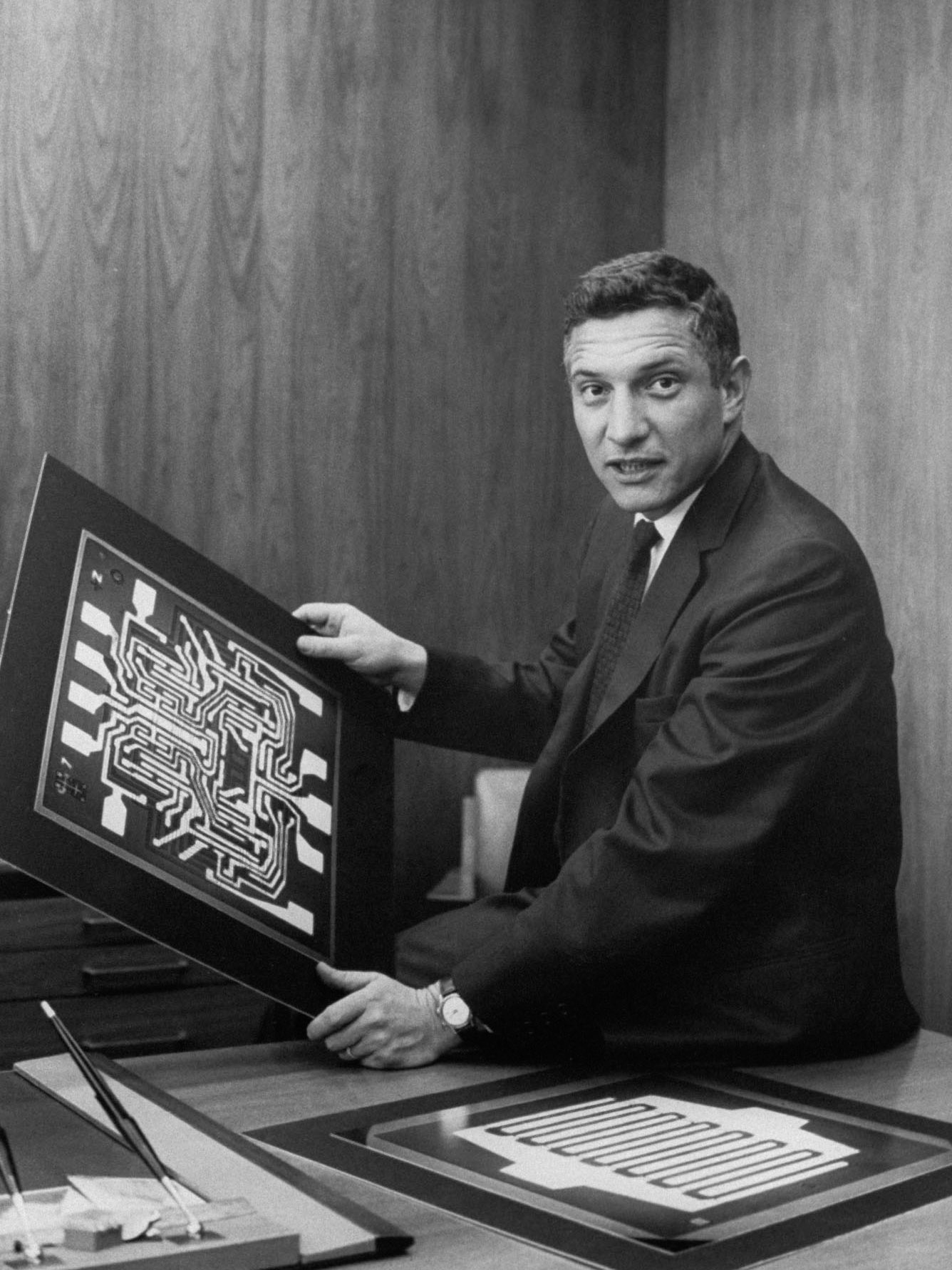 Robert Noyce en su oficina en Fairchild Semiconductor sosteniendo diagramas de semiconductores.