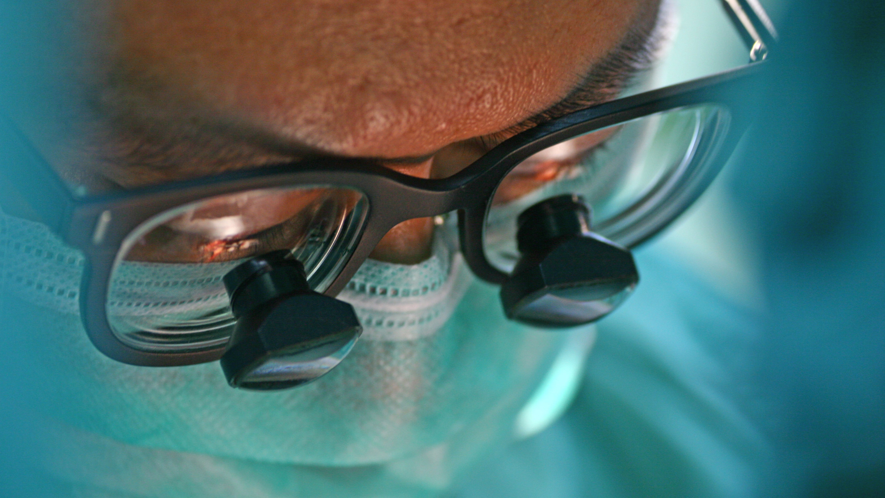 closeup on a masked surgeon&#039;s magnifying glasses