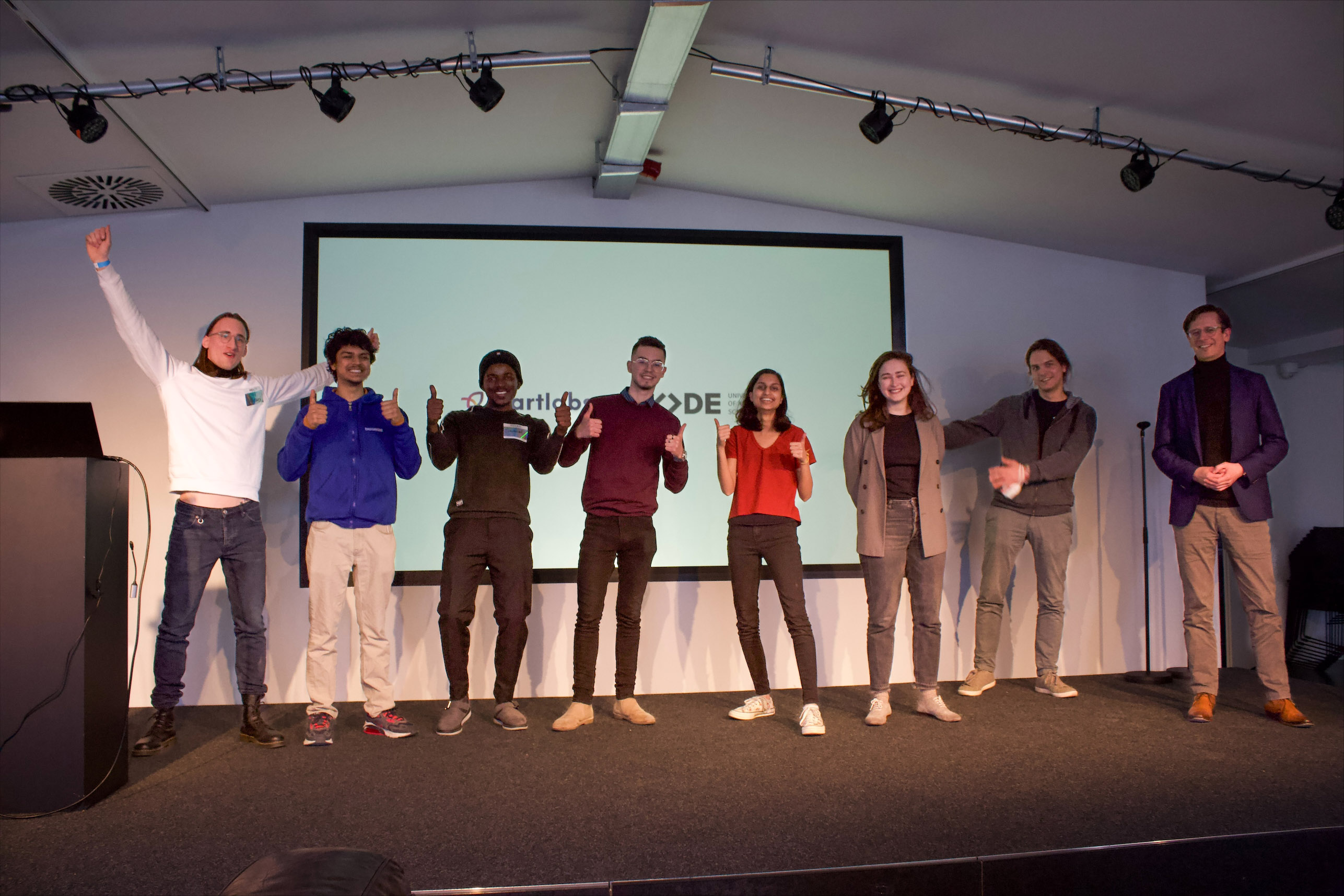 students giving a thumbs up from the stage of a presentation